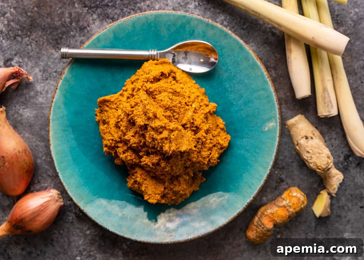 overhead: my yellow curry paste recipe on a blue plate with a spoon and ingredients surrounding it