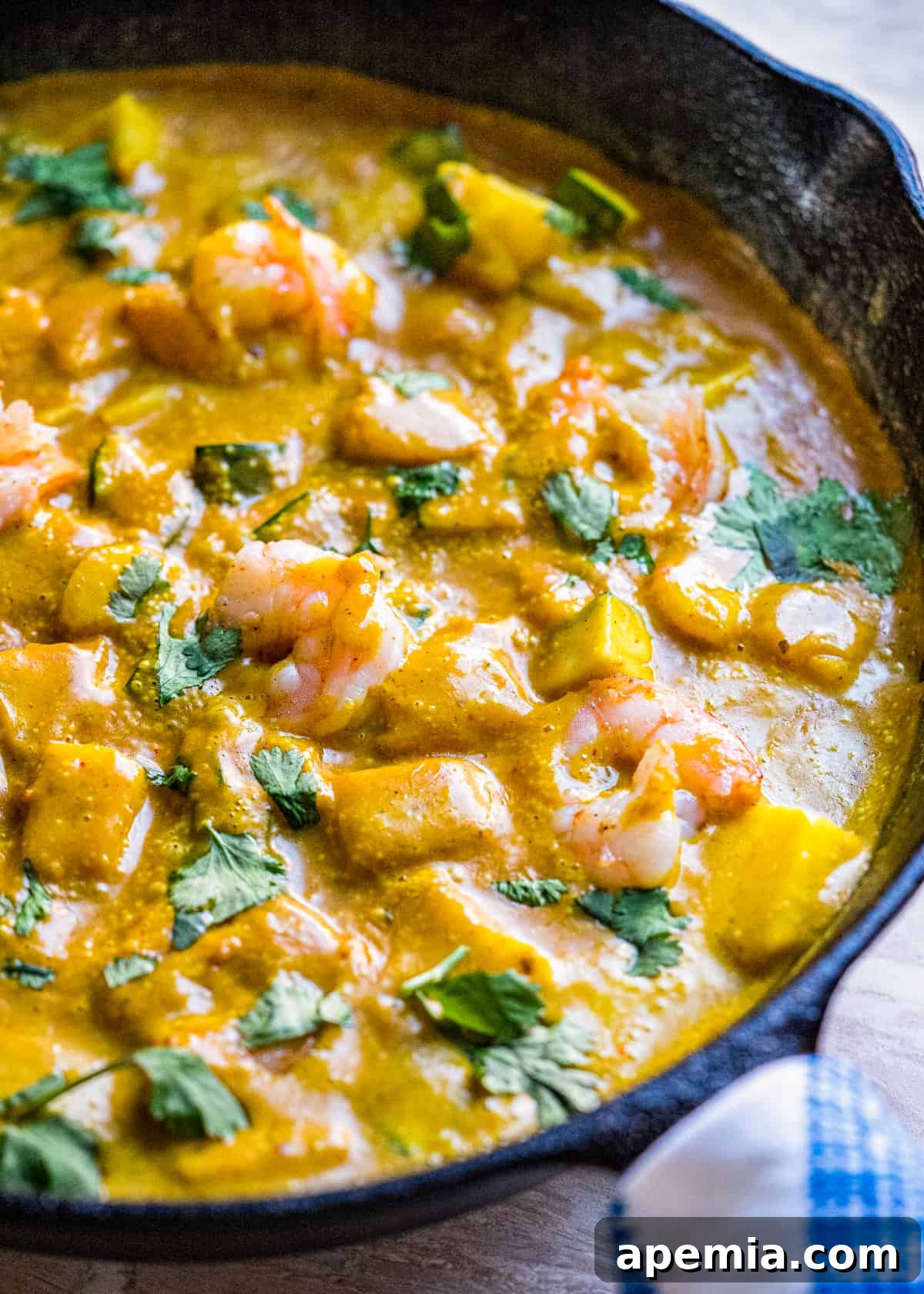 Closeup view of a skillet with cooked Thai shrimp curry, showing the creamy sauce and vibrant ingredients.