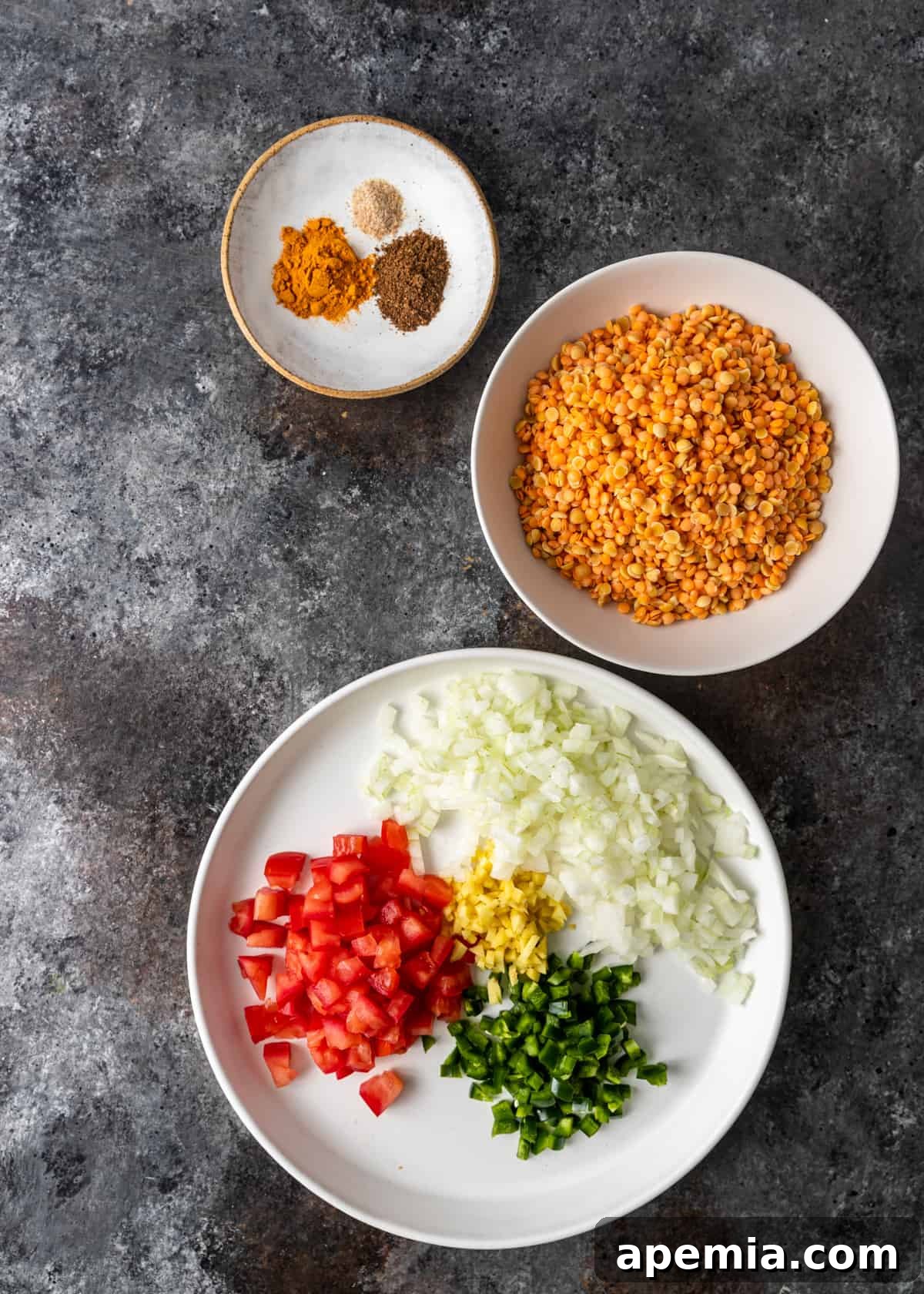 An organized display of fresh ingredients laid out on a kitchen surface, featuring various types of lentils, ripe Roma tomatoes, white onions, fresh ginger and garlic, and an assortment of whole and ground Indian spices, all meticulously arranged and ready for the preparation of Dal Tadka.