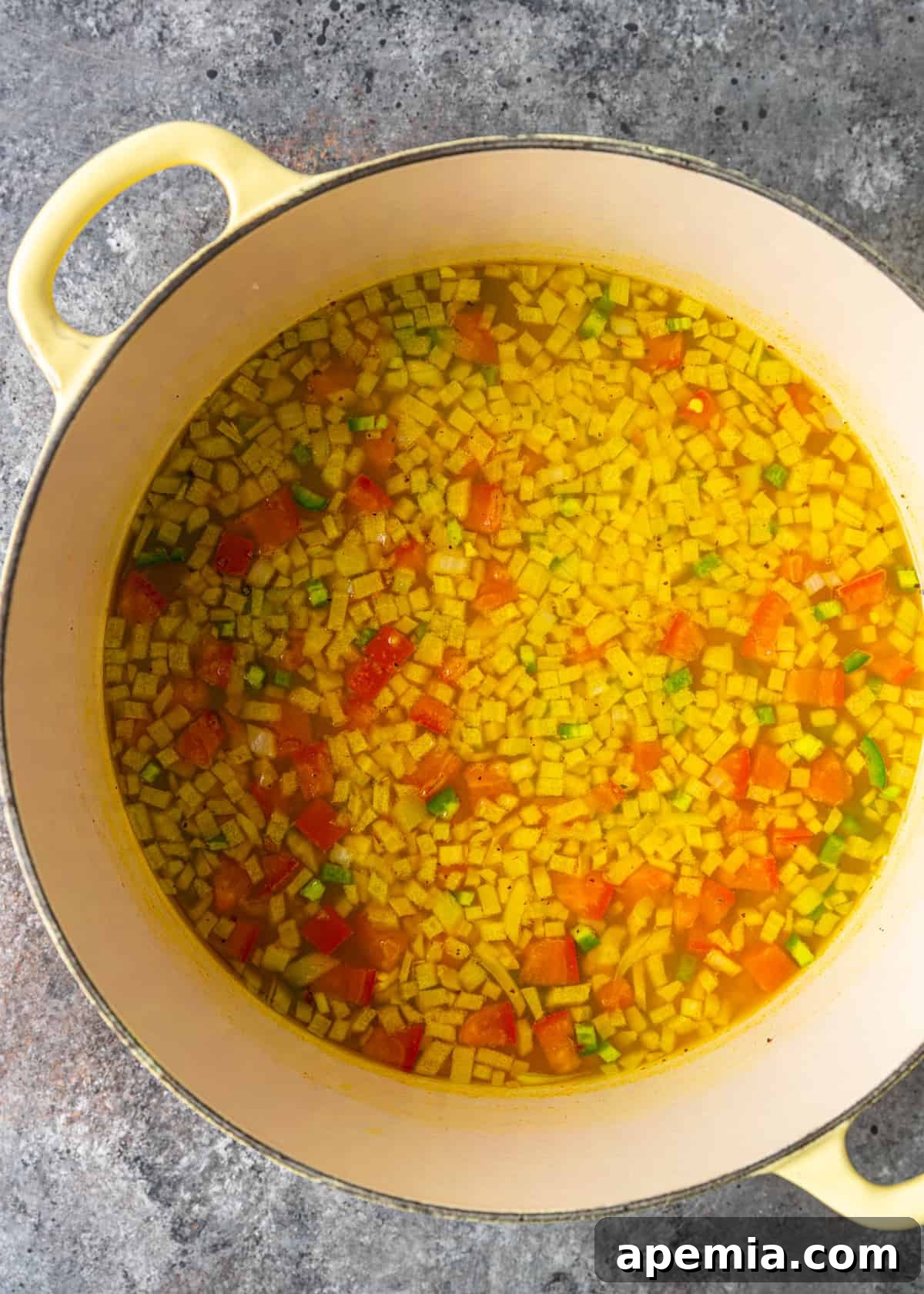 Overhead process shot demonstrating the initial stages of cooking, with aromatic ingredients like onions, chilies, and tomatoes gently simmering in a pot on the stovetop. The mixture is colorful and fragrant, indicating the development of the dal's flavor base.