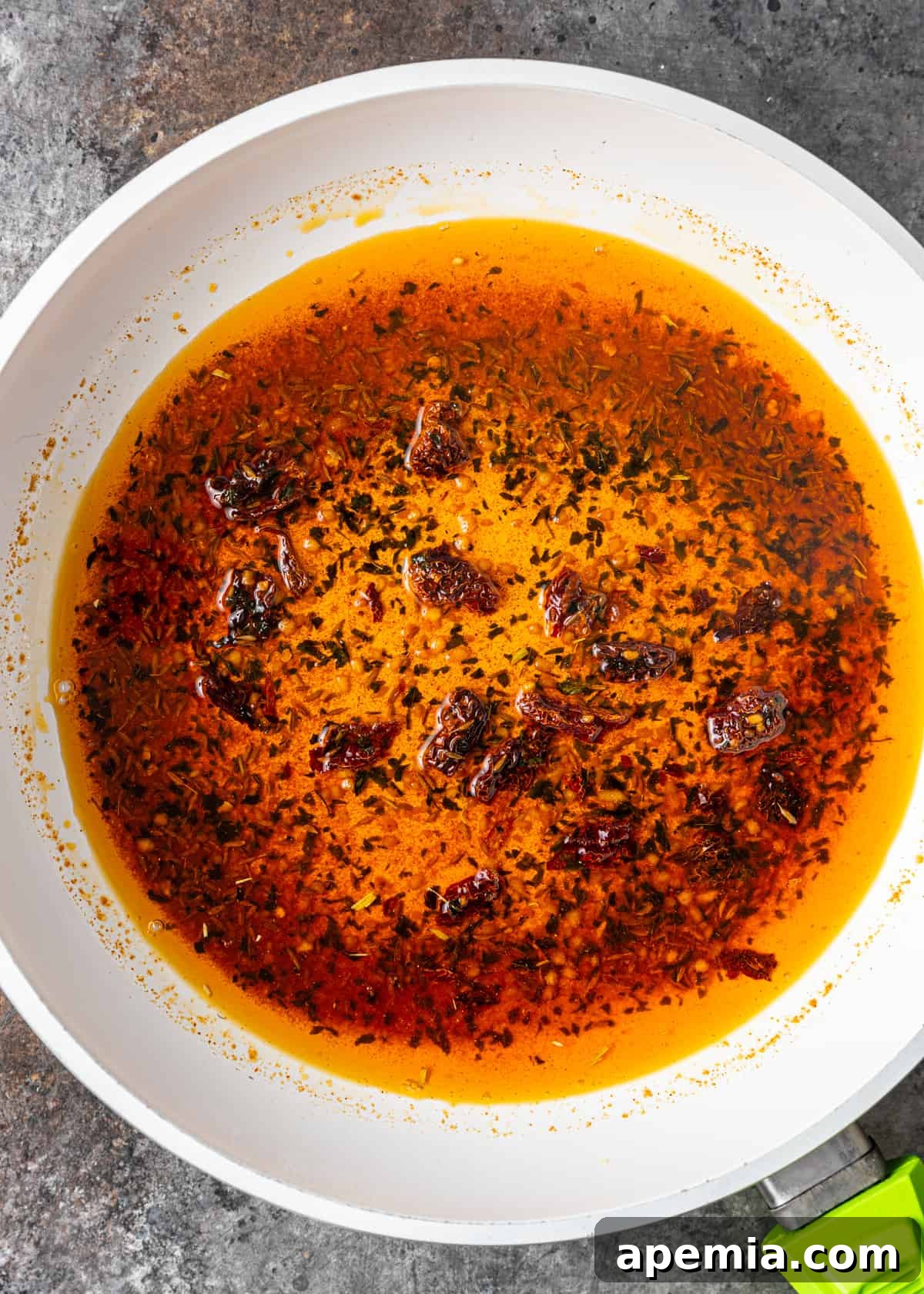 Close-up overhead view of a small skillet filled with freshly prepared tadka, featuring vibrant red dried chilies, minced garlic, and cumin seeds sizzling in hot ghee. The aromatic spices are perfectly tempered, ready to be poured over the dal.