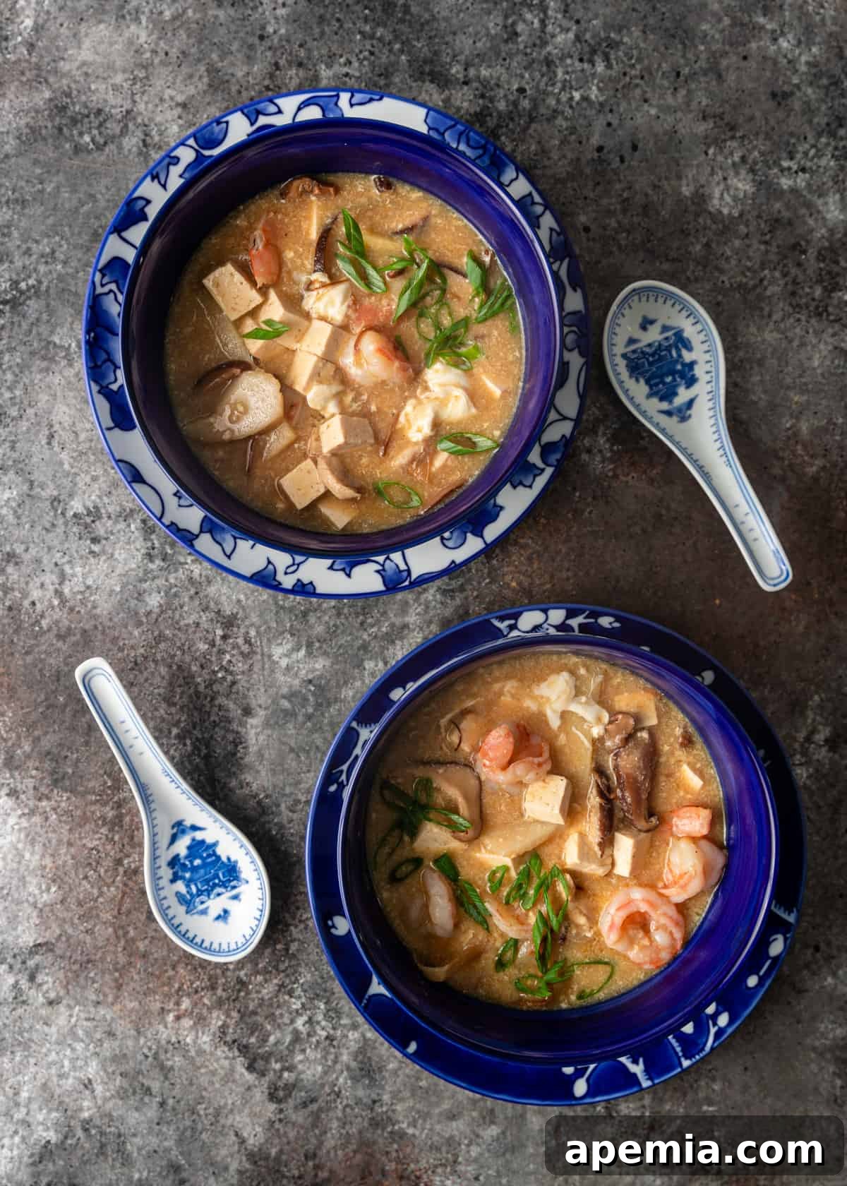 Two bowls of perfectly garnished homemade hot and sour soup, ready to be enjoyed.
