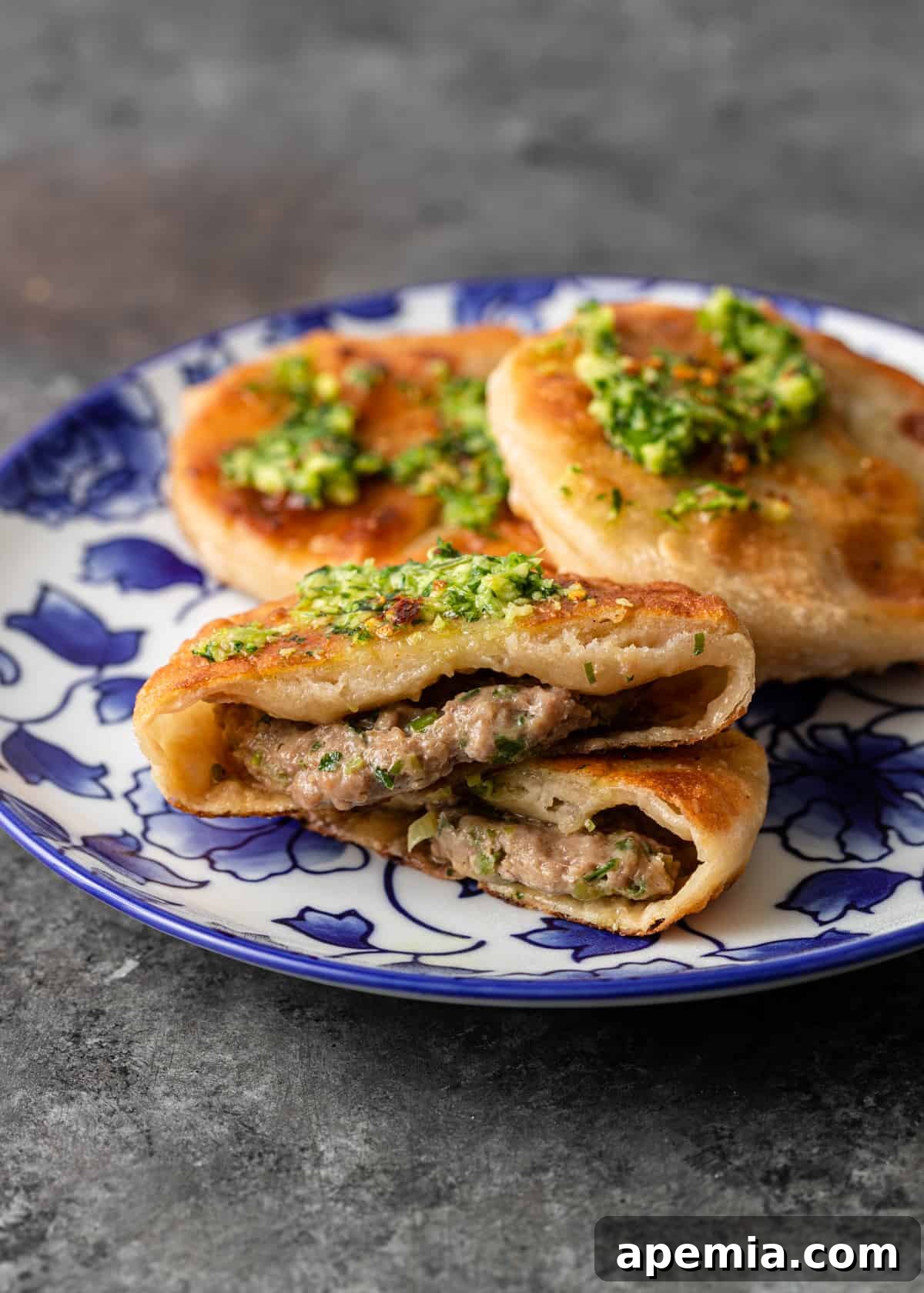 A Chinese Meat Pie cut in half, revealing the juicy pork filling and tender dough