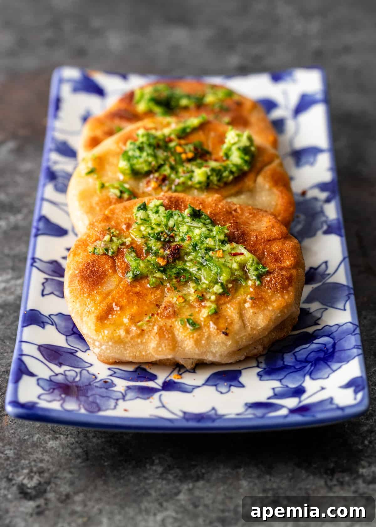 Platter with multiple golden brown Chinese Meat Pies, garnished with fresh herbs
