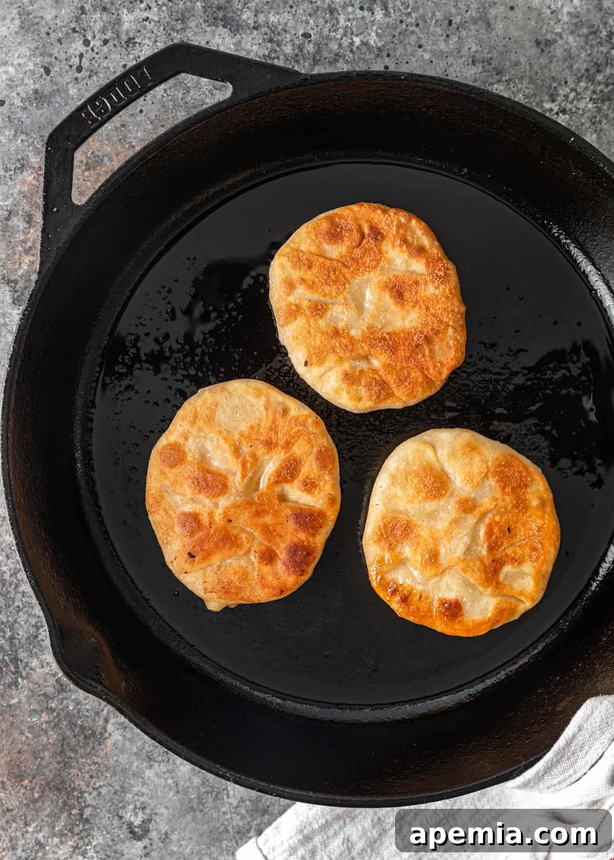 Several Chinese Meat Pies frying in a cast iron skillet, achieving a golden brown color