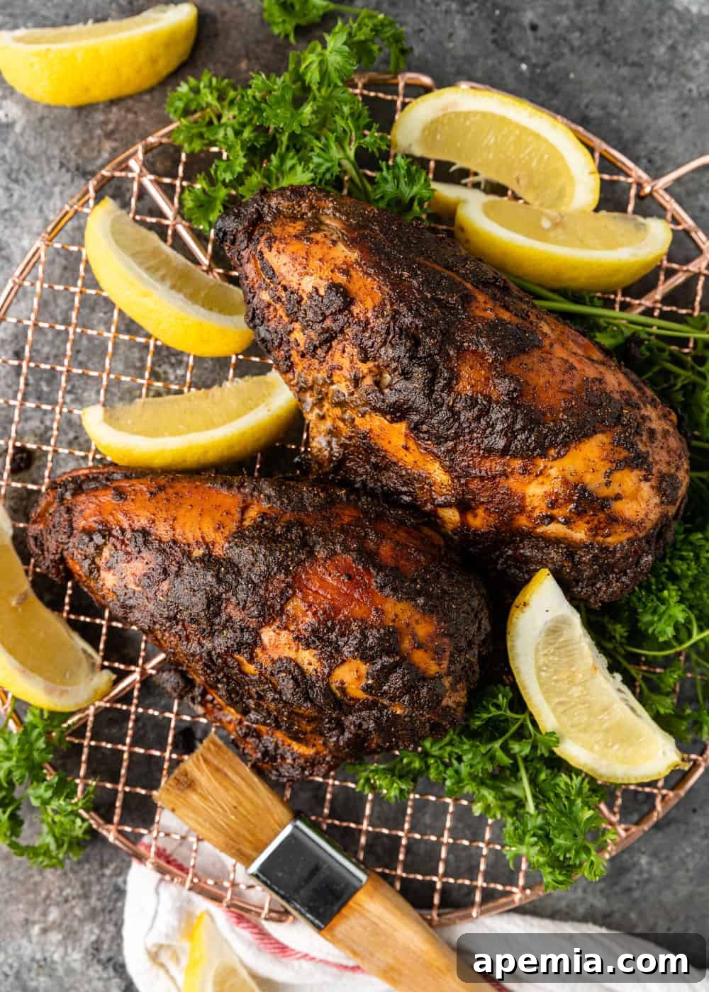 Overhead shot of Iraqi grilled chicken quarters presented on a blue patterned plate, garnished with lemon wedges and fresh parsley.