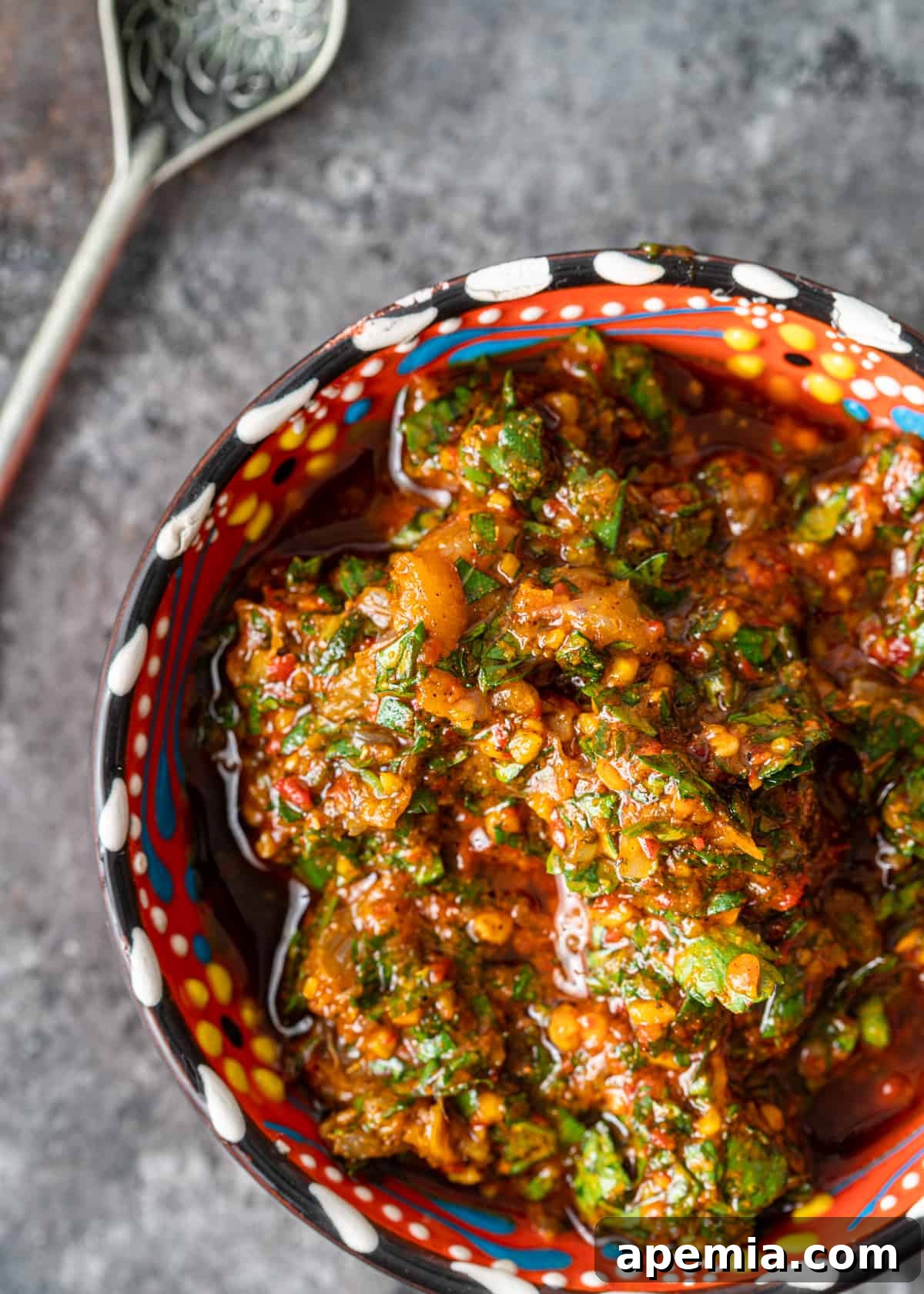 Overhead shot of a small, vibrantly colored ceramic bowl filled with homemade chermoula, highlighting its fresh appeal.