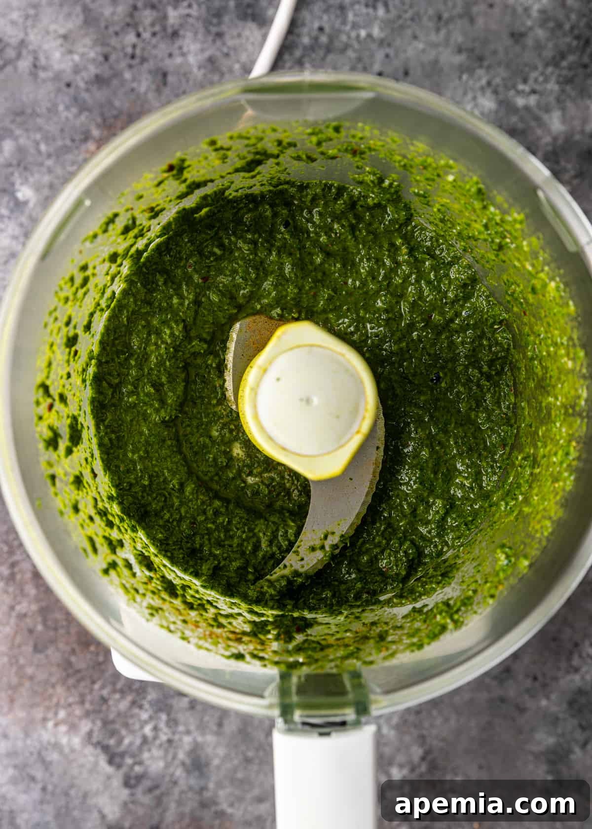 Overhead view: blended ingredients for green chermoula in a food processor, showing a smooth, vibrant texture.