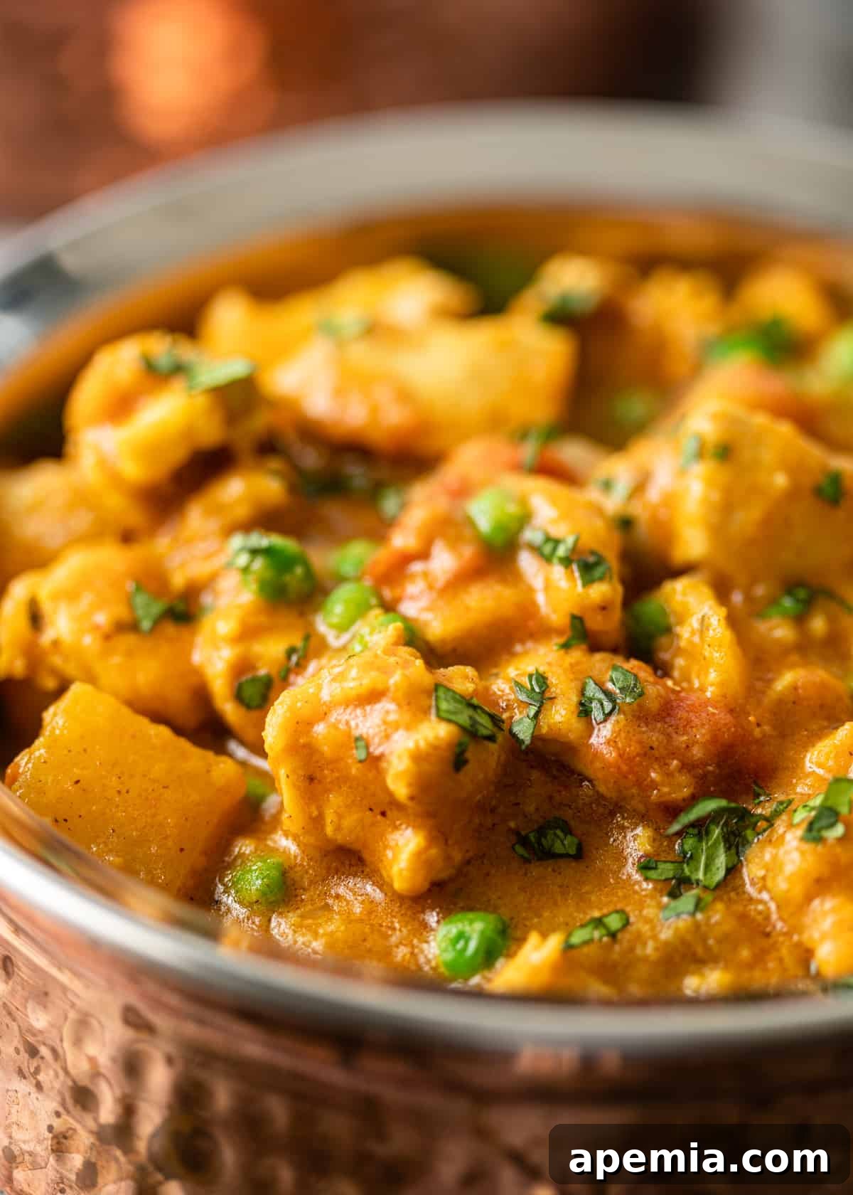 Closeup shot of Indian chicken curry, beautifully garnished with fresh herbs on top, highlighting the creamy sauce and tender chicken