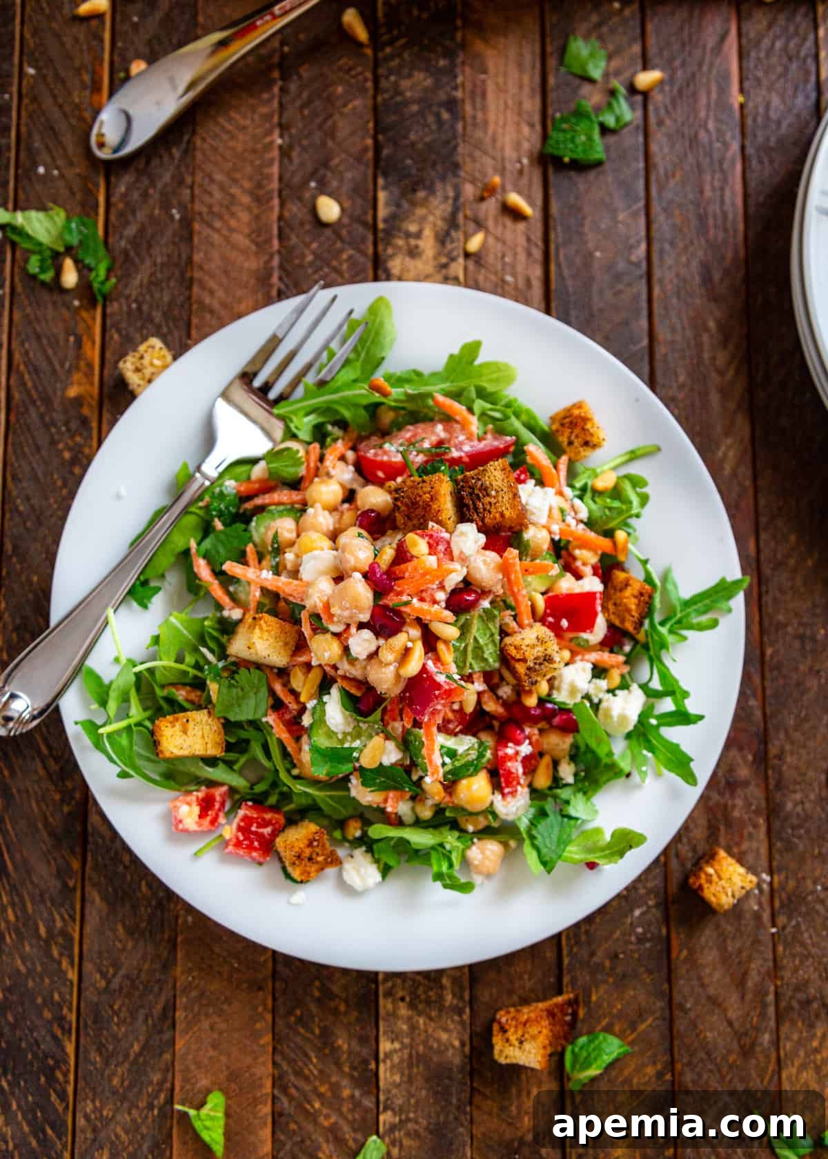 overhead of Mediterranean salad with chickpeas, carrots, and red bell peppers served on white plate