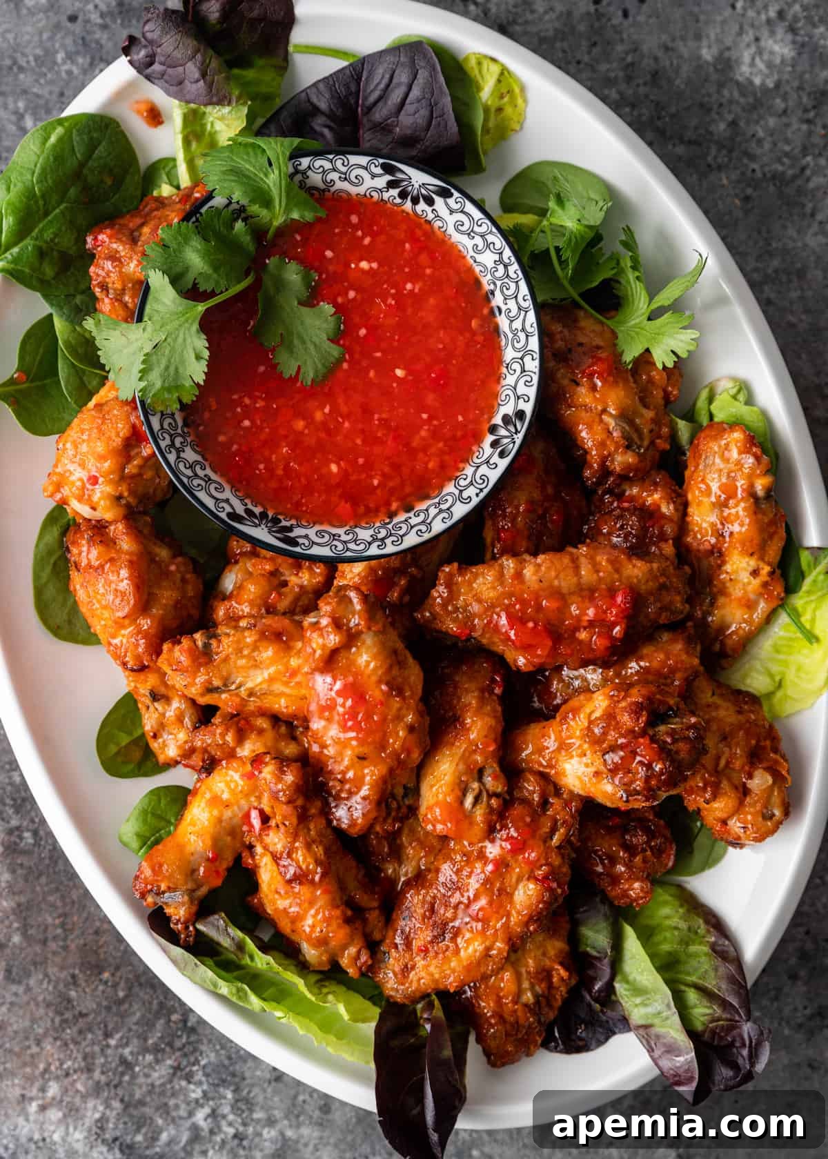 overhead: sweet chili sauce and chicken wings on a platter