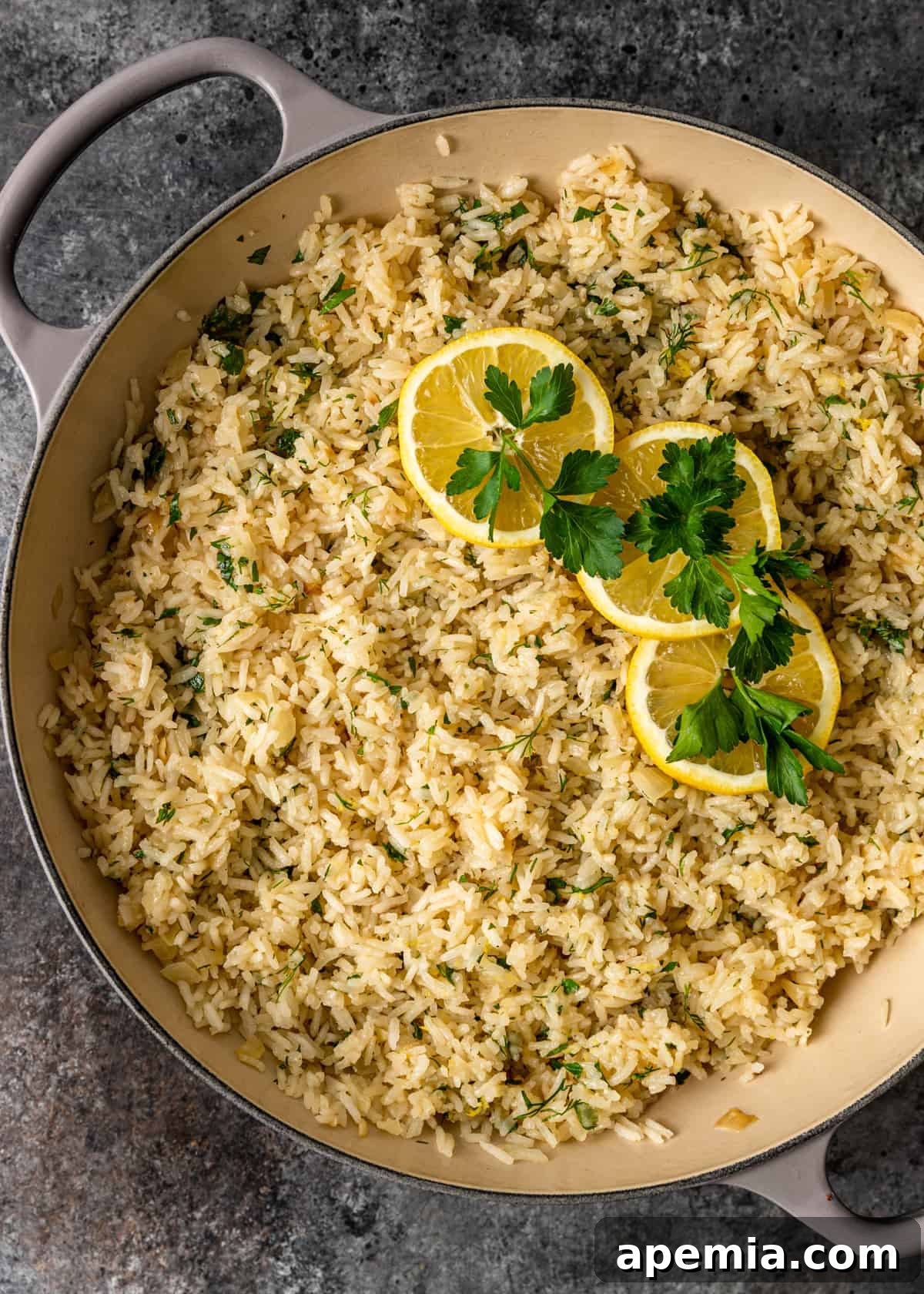 An inviting overhead shot of a large pot filled with fragrant Greek lemon rice, artfully arranged with fresh lemon wedges and green herbs.