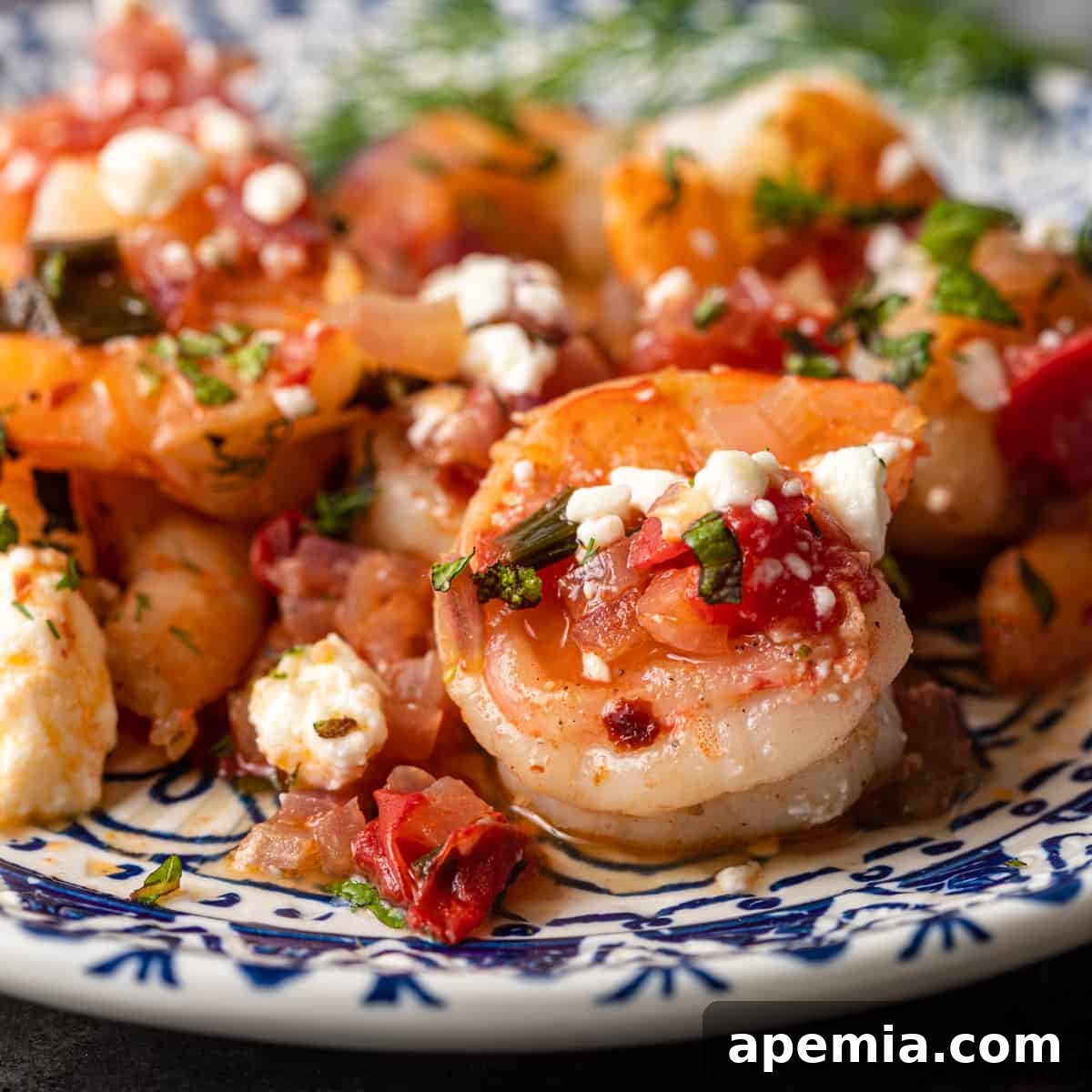 Closeup of a plate of vibrant Greek Shrimp Saganaki, garnished with fresh herbs.