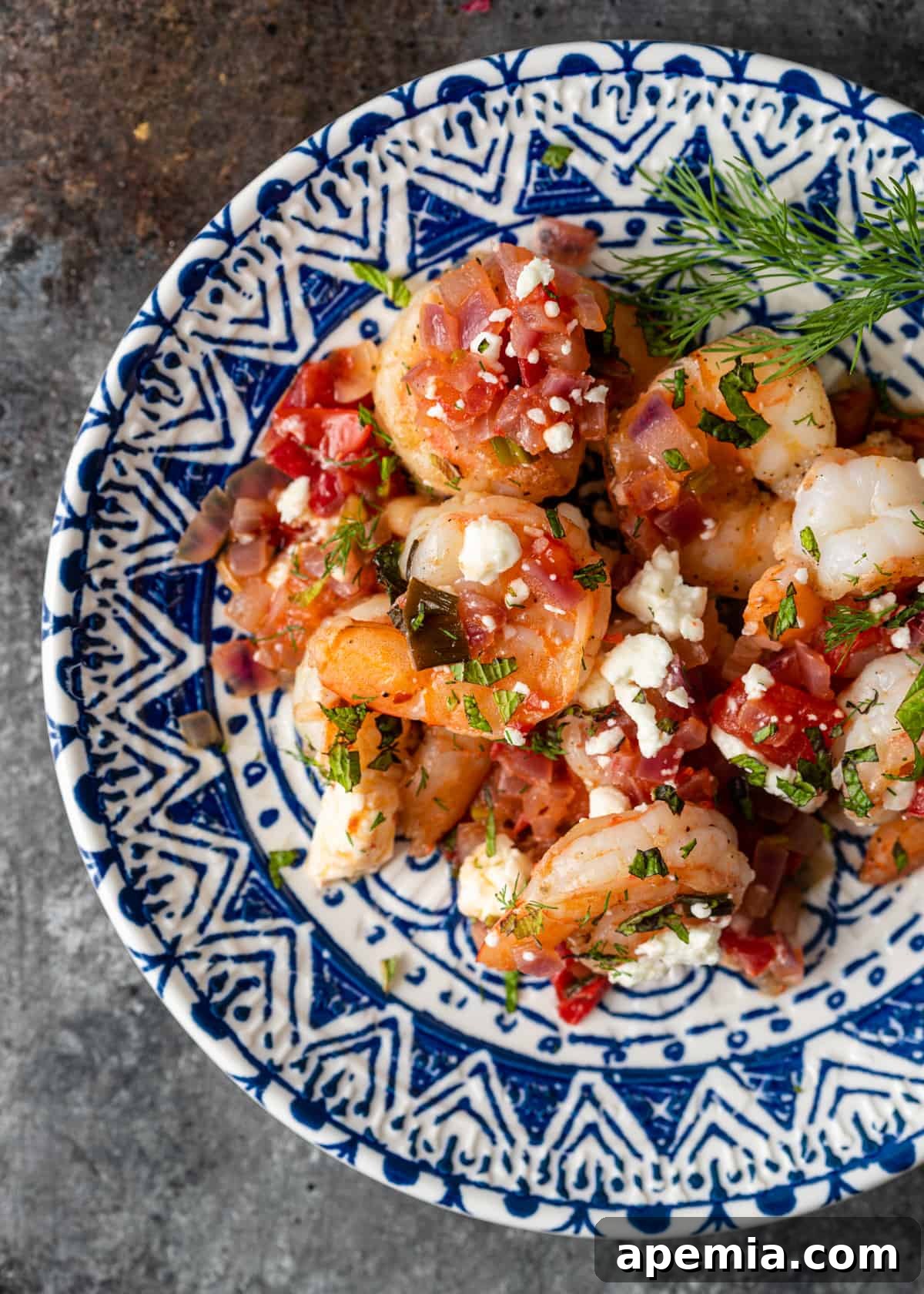 Overhead view of a single serving of Shrimp Saganaki on a blue and white ceramic plate, ready to be enjoyed.