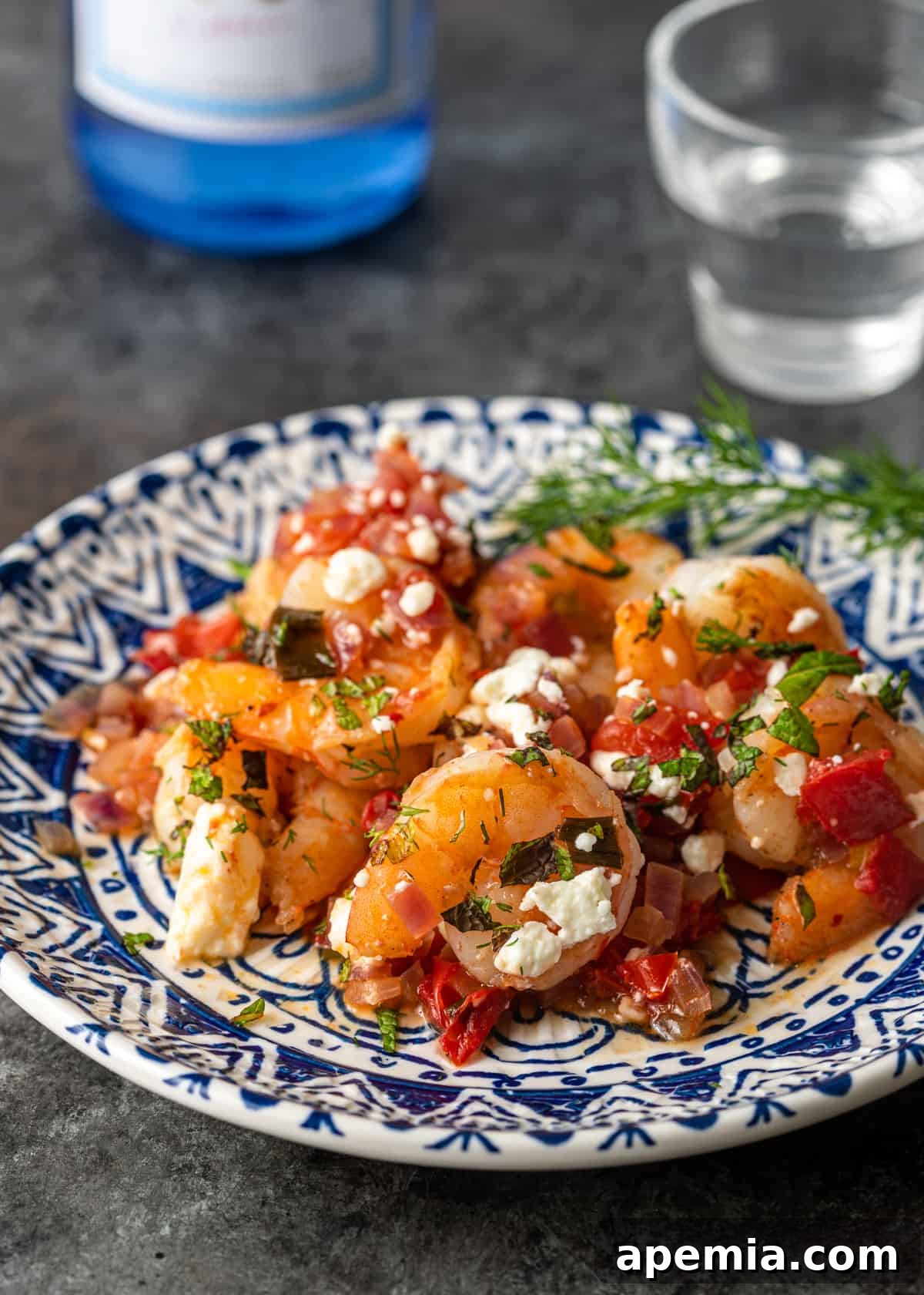 A beautifully plated serving of Greek Shrimp Saganaki on a white and blue patterned plate, ready for consumption.