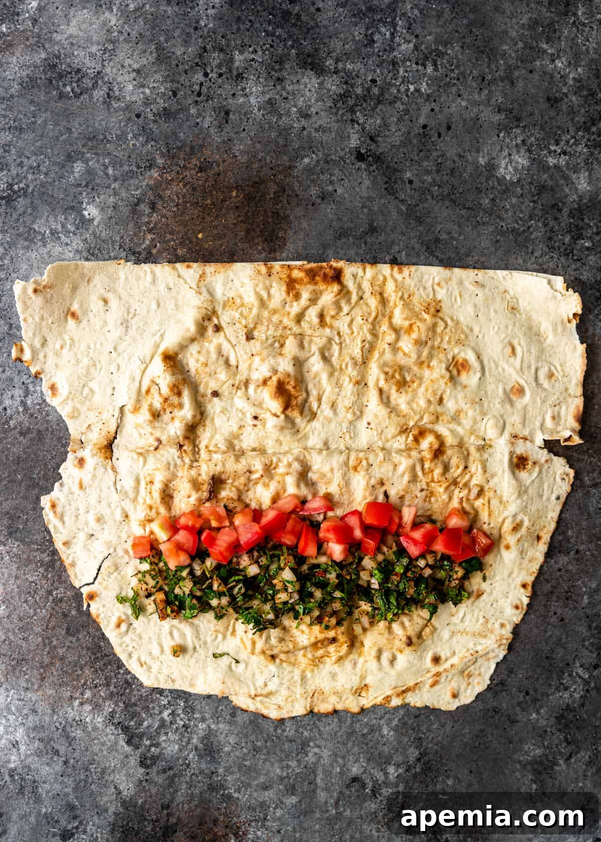 overhead process shot: chopped tomatoes added to lavish wrap