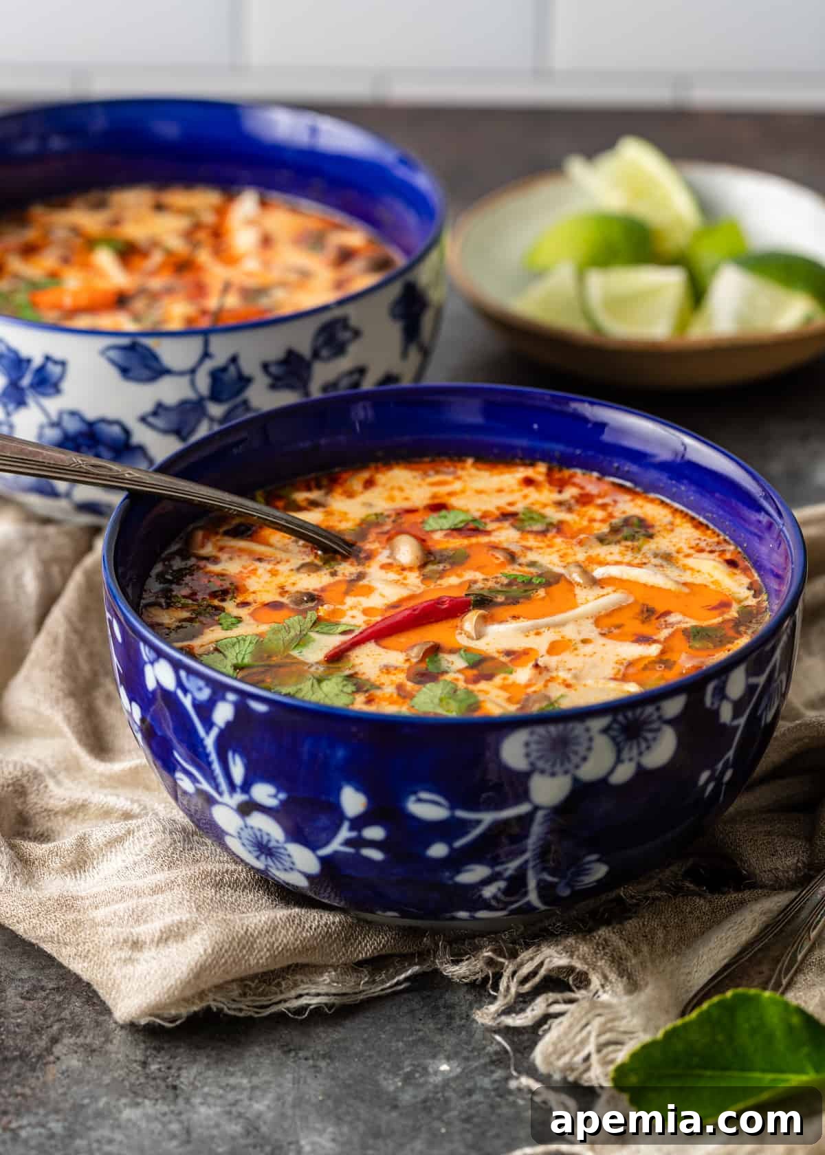 Fragrant Thai Coconut Chicken Soup 3 closeup side view: tom kha gai soup in a blue bowl with a spoon