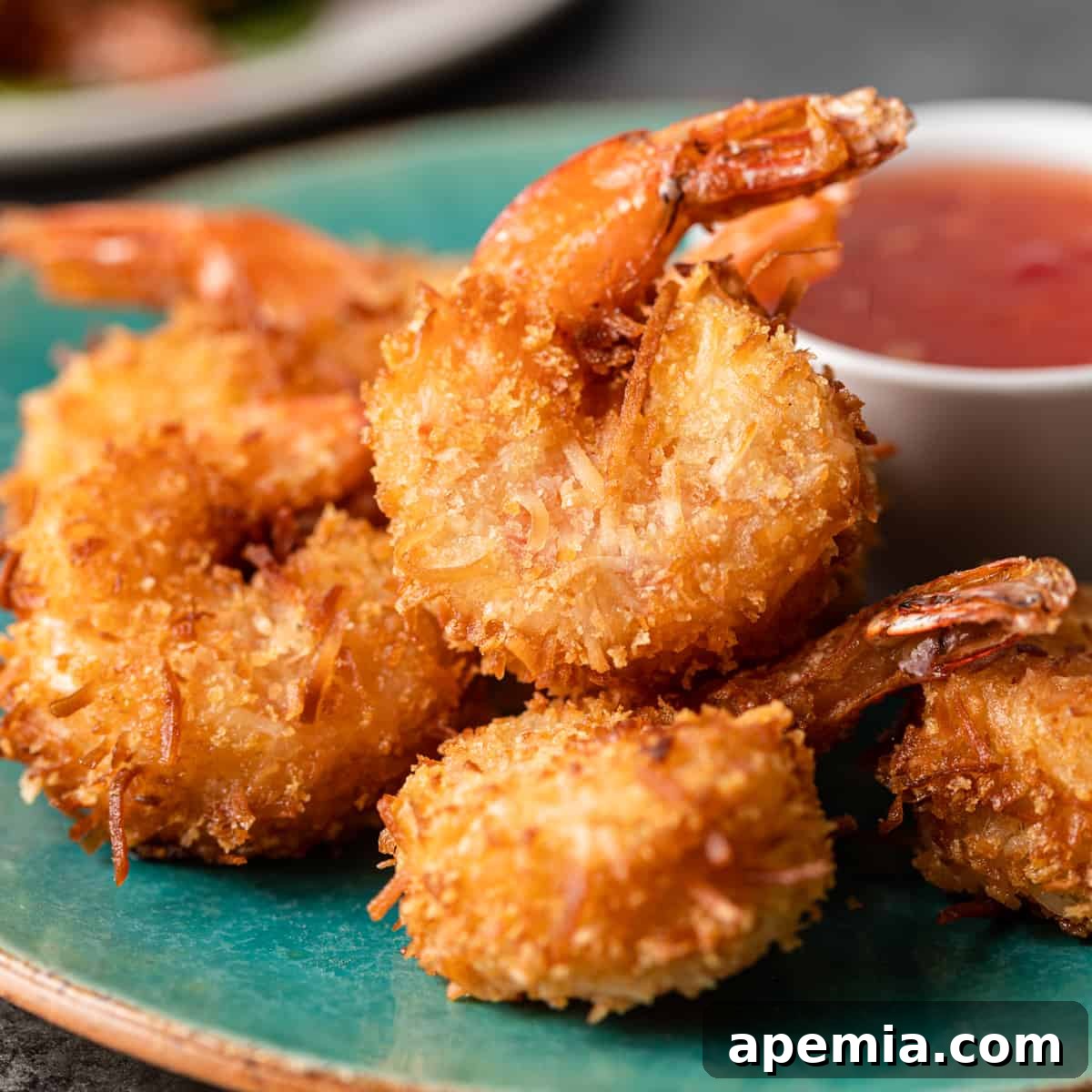 Sweet Coconut Crunch Shrimp 2 Closeup: a platter of crispy coconut shrimp, golden brown and perfectly cooked, garnished with fresh herbs.