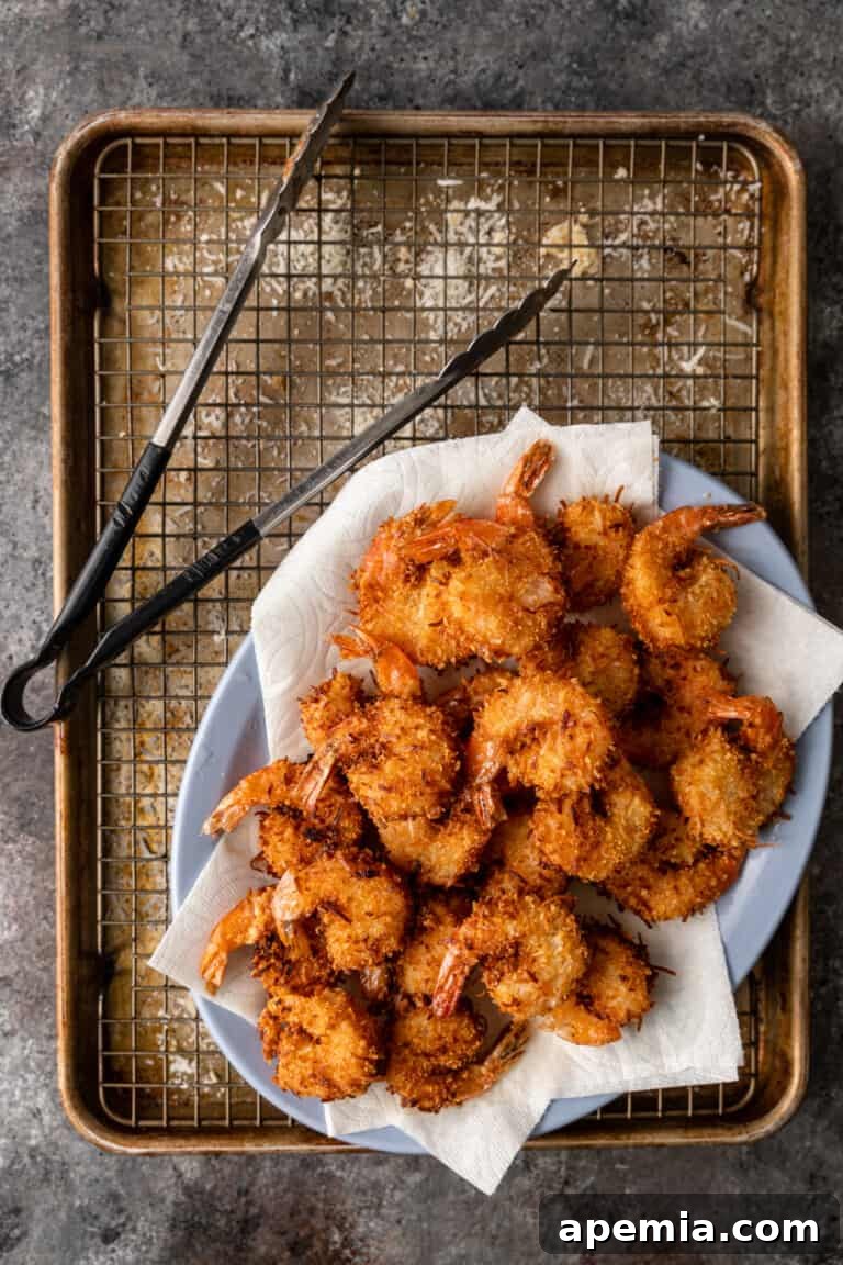 Sweet Coconut Crunch Shrimp 6 Overhead process shot: freshly fried golden-brown coconut shrimp draining on paper towels after being removed from the oil.