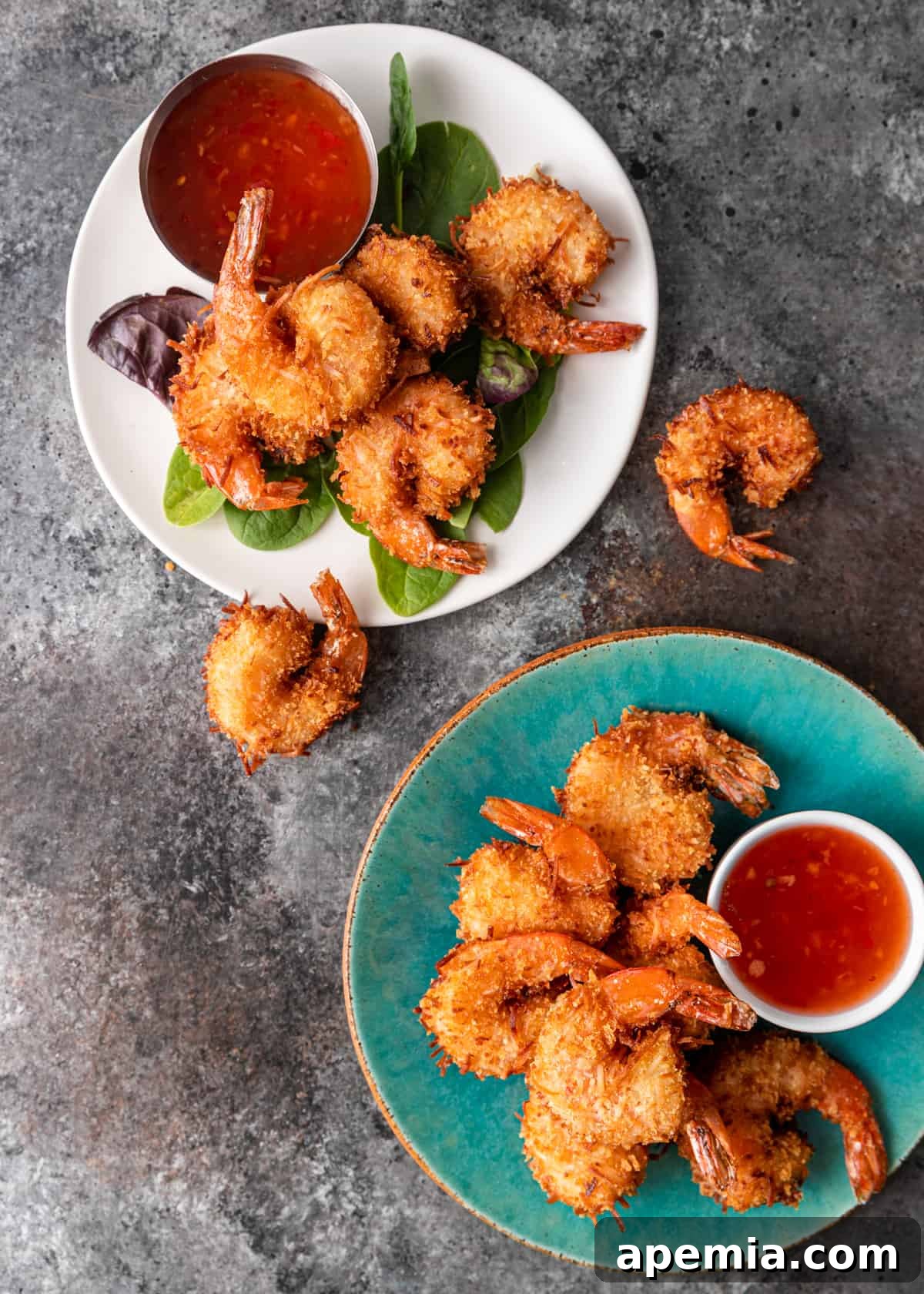 Sweet Coconut Crunch Shrimp 7 Overhead shot: two small plates piled high with crispy coconut shrimp and dipping sauces, with extra shrimp on the side.