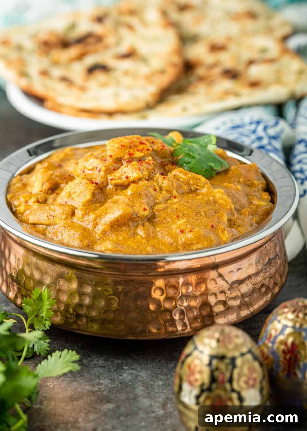 copper serving bowl filled with Indian chicken curry in a creamy sauce