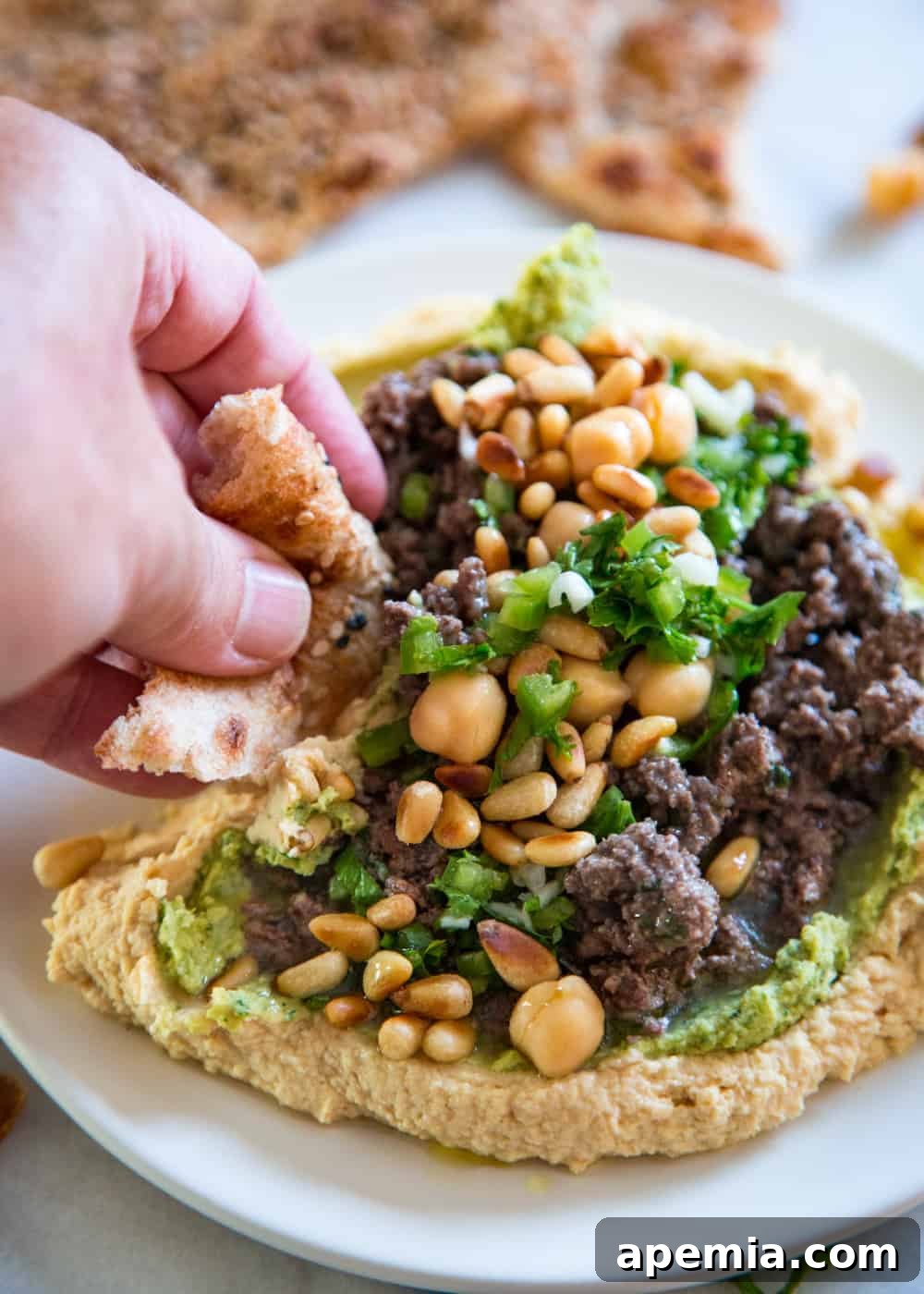 man's hand dipping flatbread into a Lebanese chickpea dip appetizer