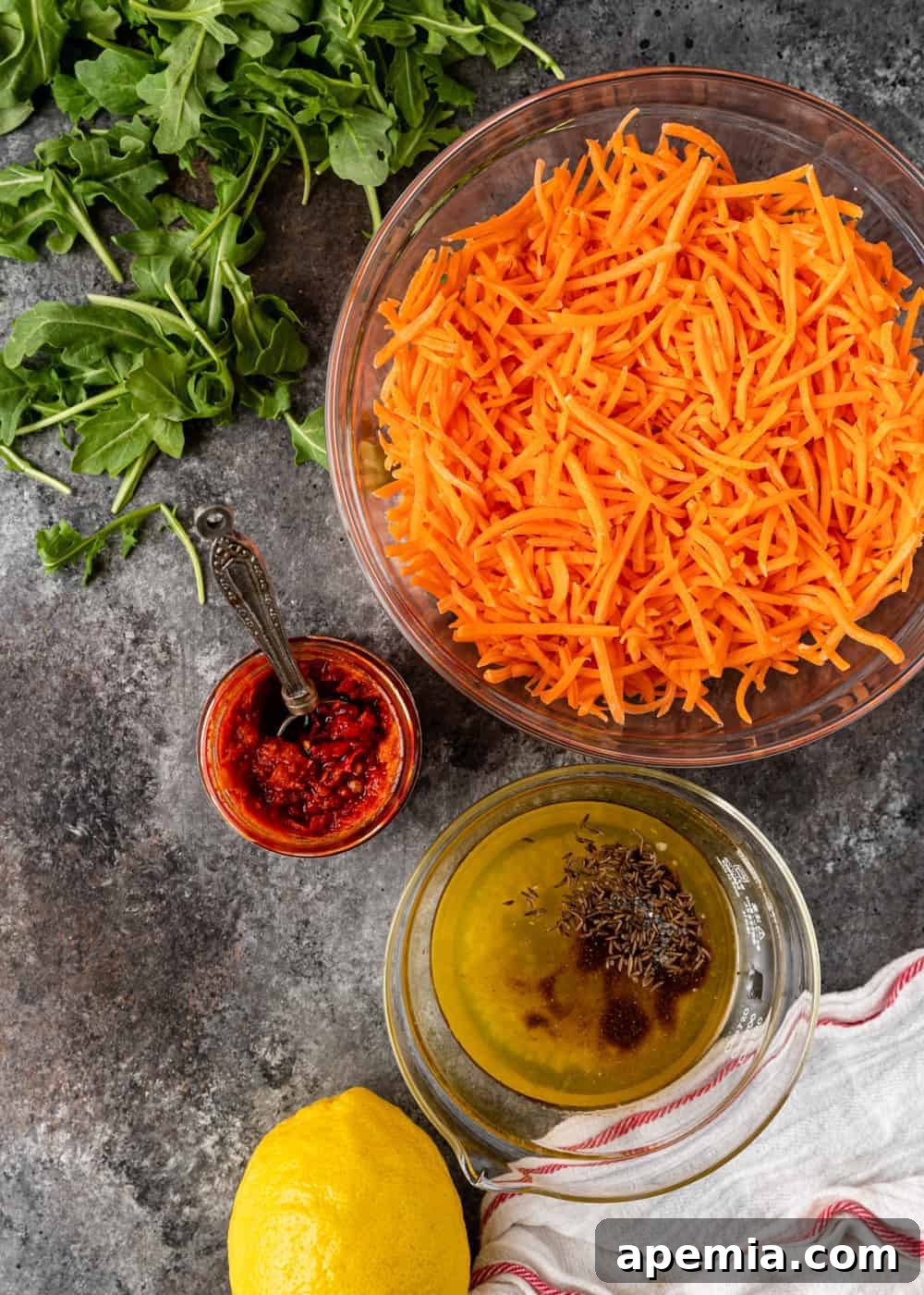 overhead: bowls of harissa carrots and vinaigrette for carrot salad preparation