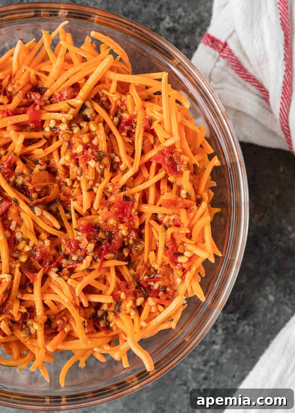 overhead: shredded raw carrot salad in glass bowl, ready for chilling