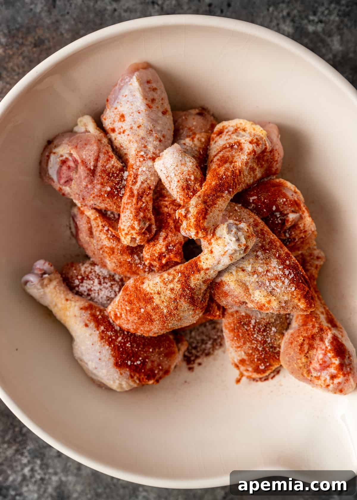 Fiery Peri Peri Chicken 4 Overhead view of raw chicken drumsticks in a bowl, generously seasoned