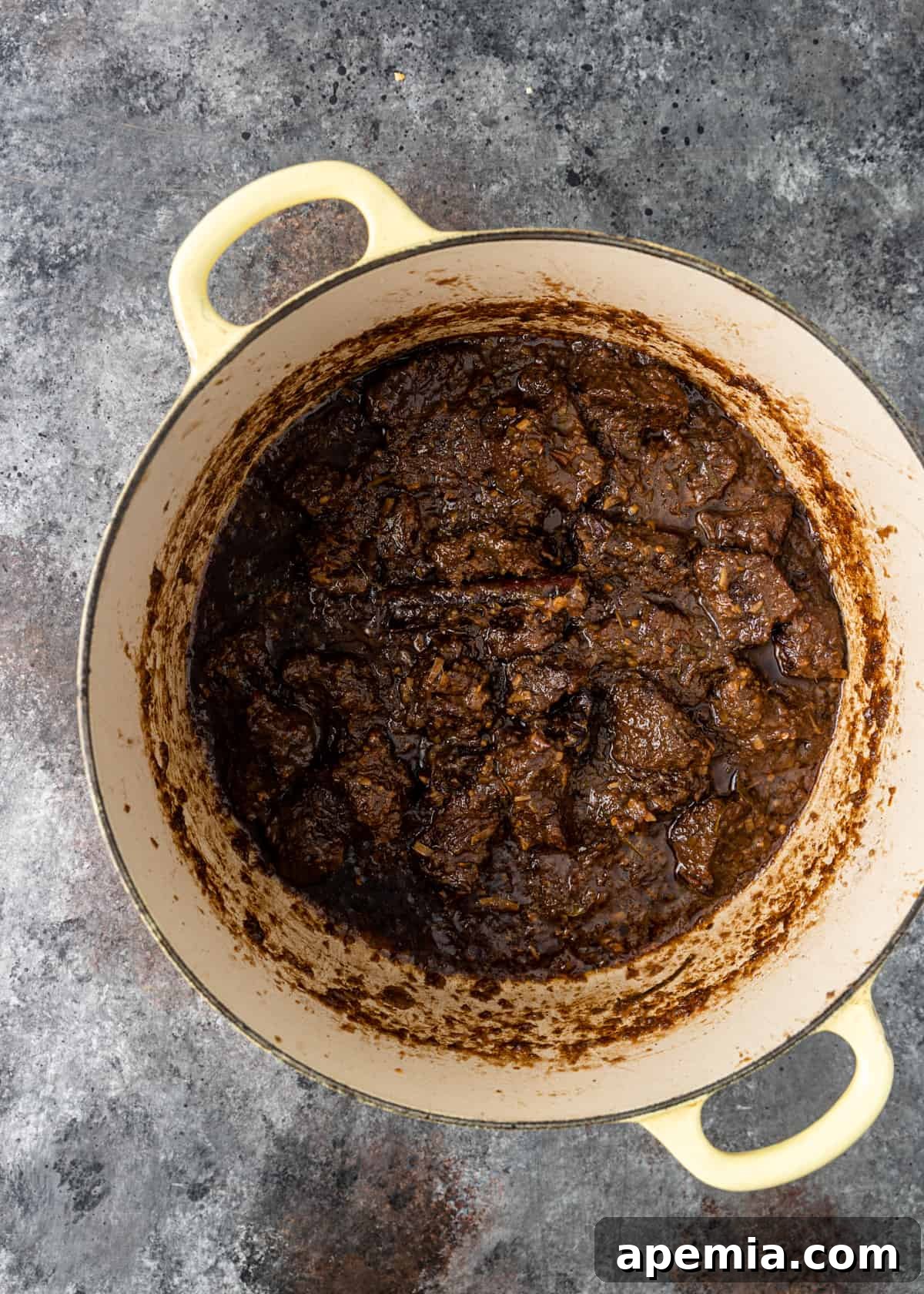 Overhead process shot: Beef Rendang simmering vigorously uncovered, as the sauce visibly reduces and thickens to its rich, signature dry consistency.