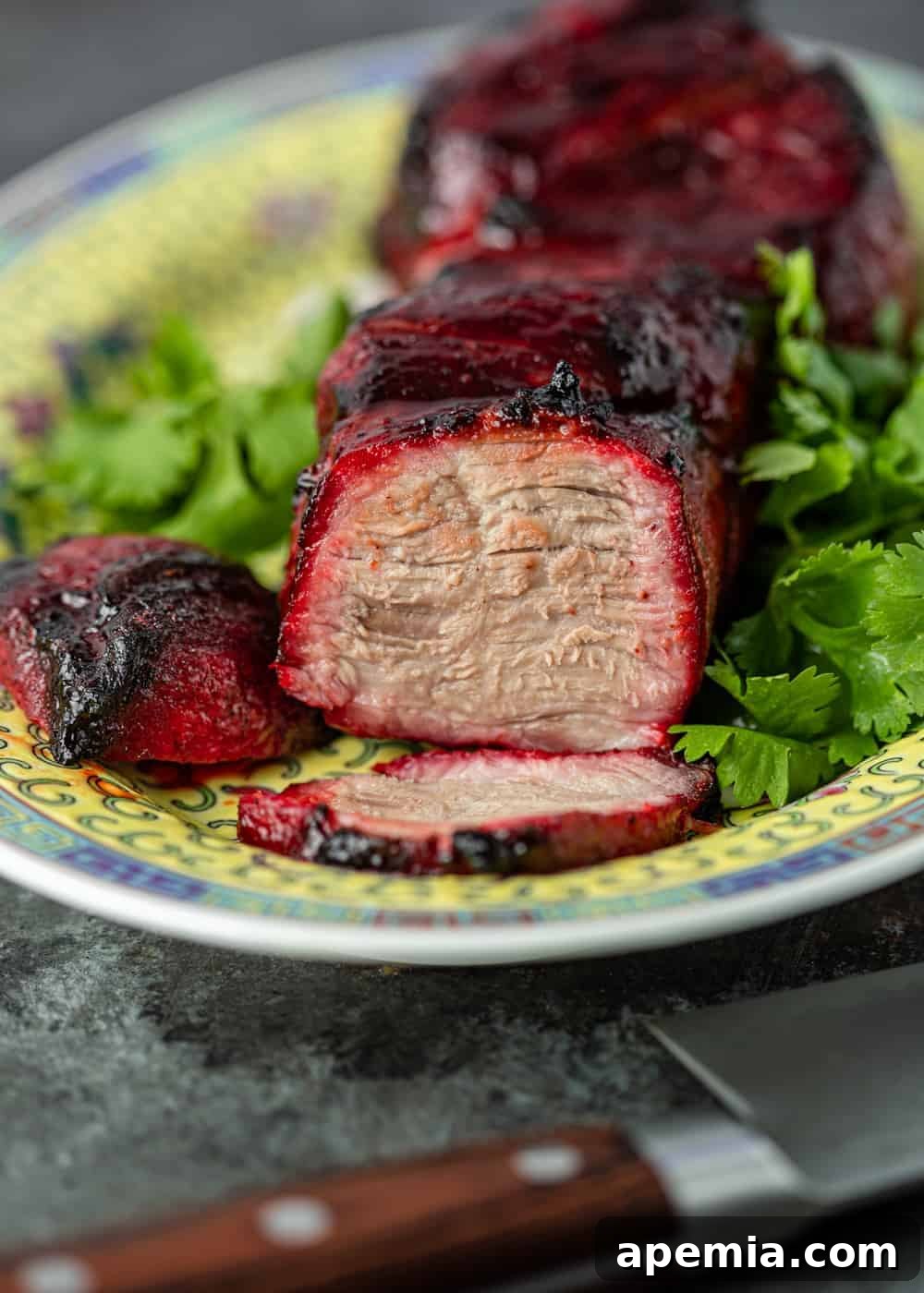 Side view of perfectly sliced Char Siu pork on a serving platter, revealing its juicy, tender interior and rich red color, ready to be enjoyed.