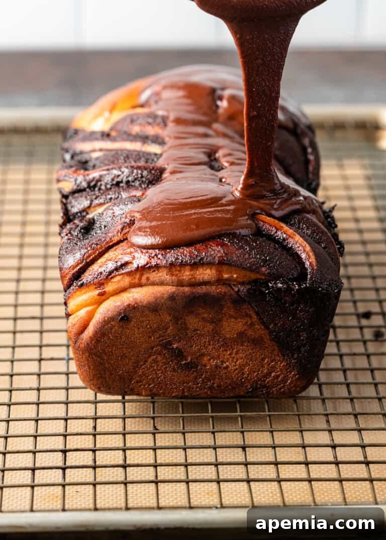 Overhead process shot: More chocolate glaze being poured, ensuring full coverage of the baked babka.