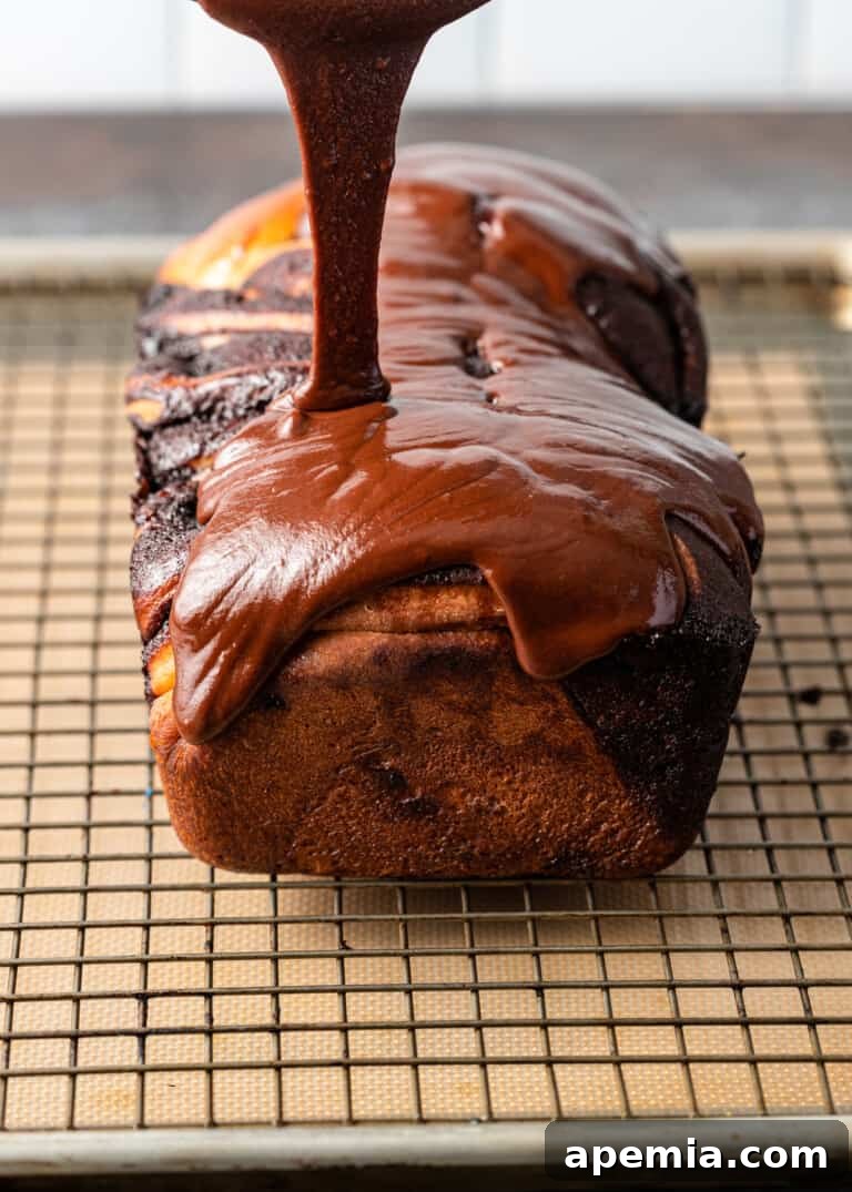 Overhead process shot: The babka continues to be glazed, illustrating the thick, luscious coating.