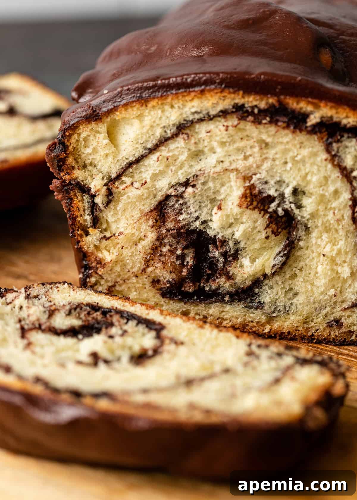 Close-up view of a baked chocolate babka loaf, with several expertly sliced pieces arranged on a wooden cutting board, highlighting the intricate chocolate swirls.
