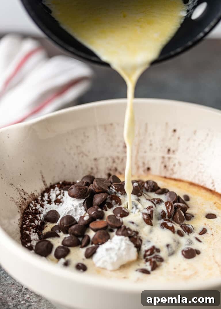 Close-up process shot: Melted butter and cream being poured into a bowl with chocolate, beginning to form the rich filling.