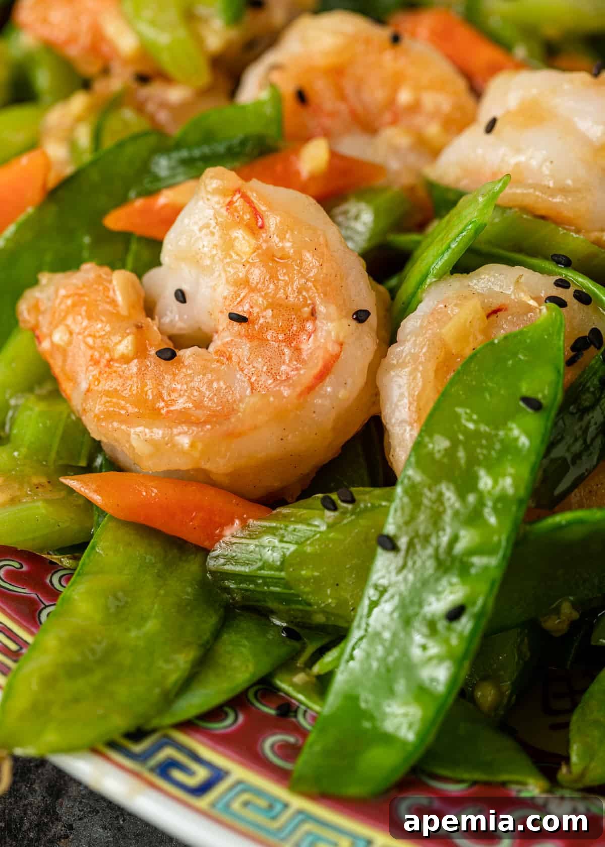 A serving bowl filled with the completed shrimp and snow peas stir-fry, garnished and ready for the table.