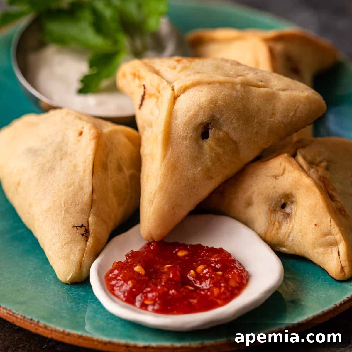 closeup: fatayer meat hand pies on plate with red shatta sauce