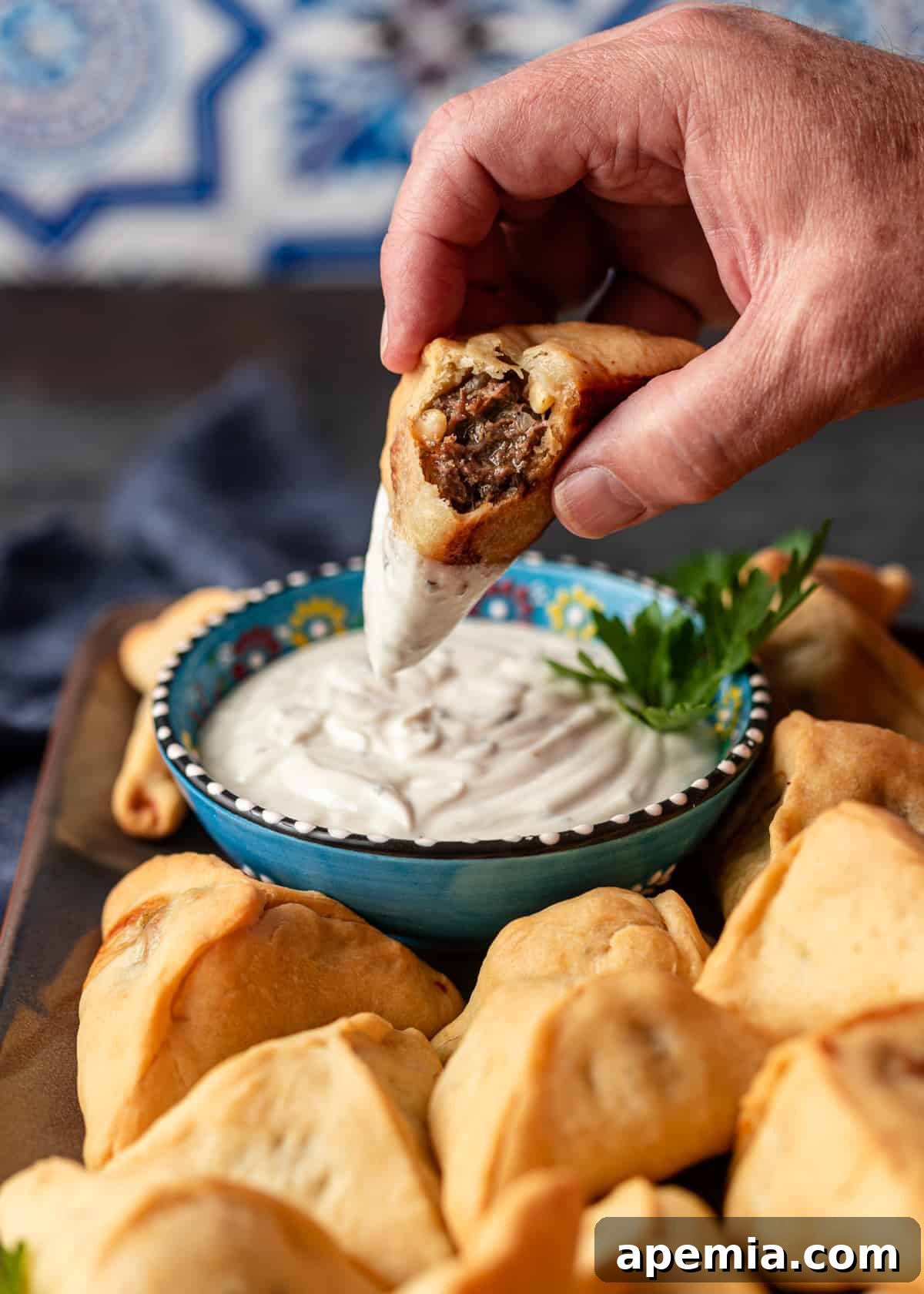 dipping a lebanese meat pie into sauce