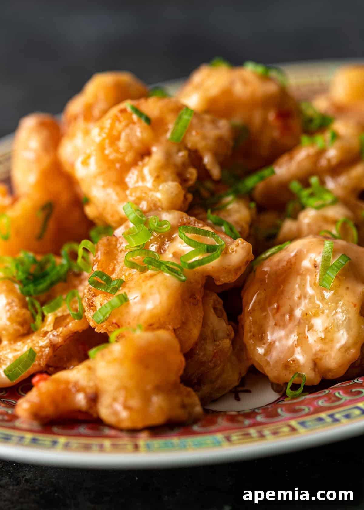 closeup: bang bang shrimp with sliced green onions on top on colorful platter