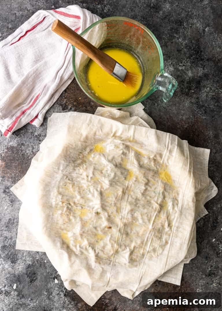 Process shot: Adding more buttered filo sheets to cover the chicken filling, preparing to seal the pastilla.