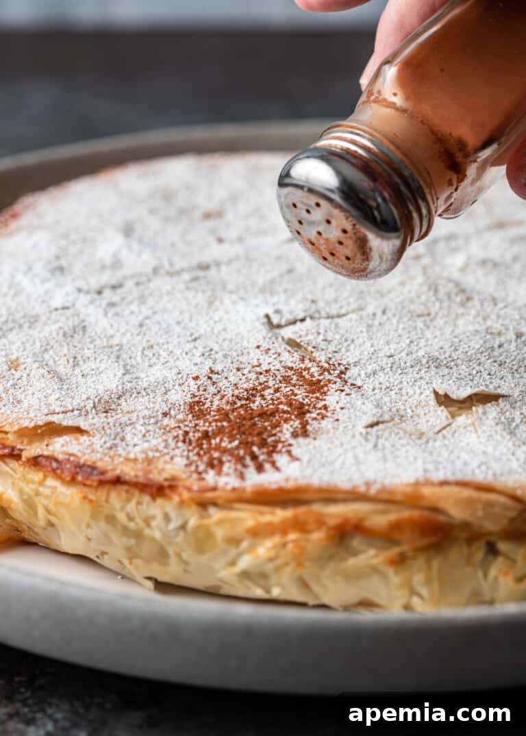 Process shot: Generously sprinkling the baked Pastilla with powdered sugar and cinnamon, creating a stunning visual and flavor contrast.