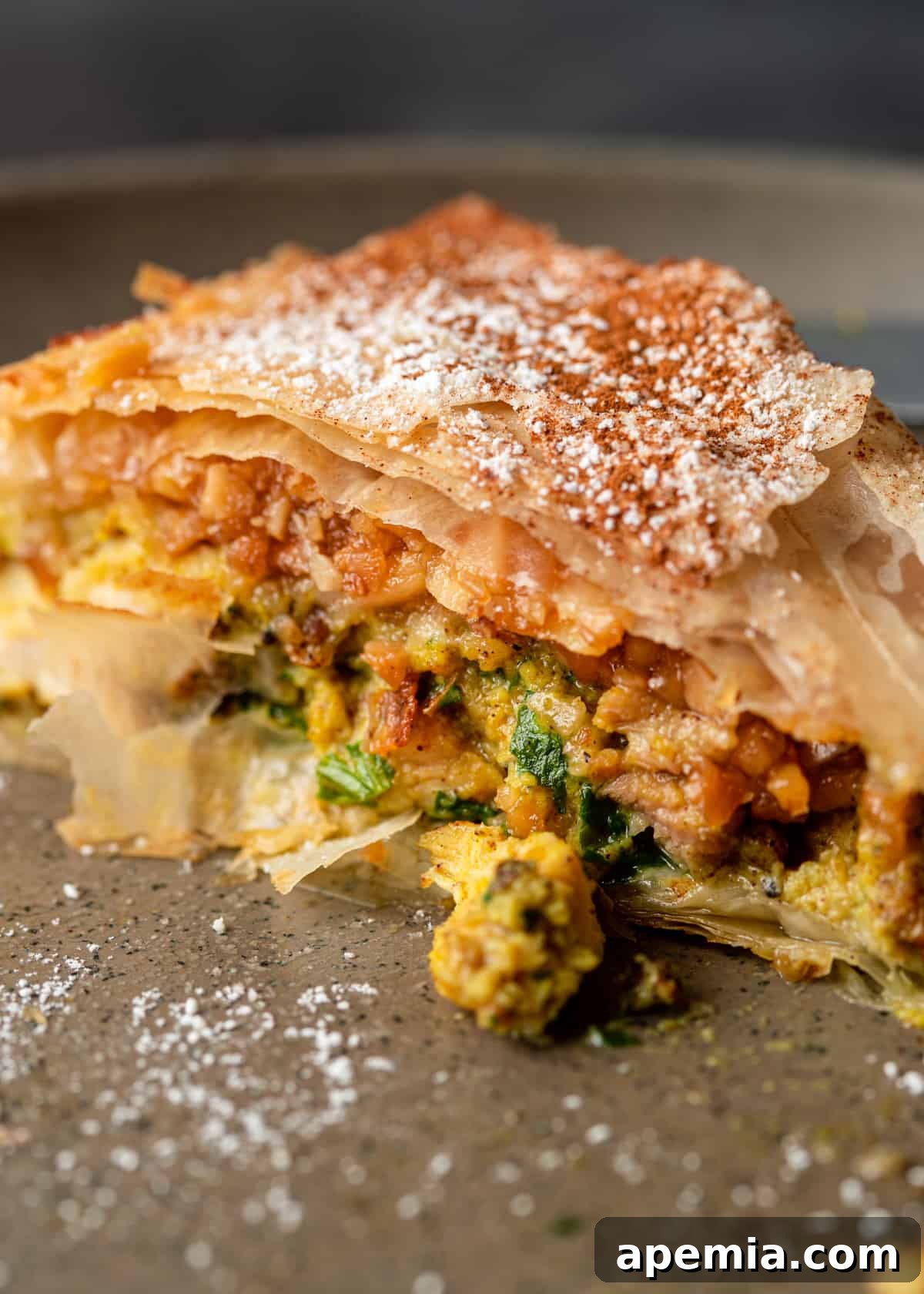 A close-up view of a slice of Moroccan Pastilla, highlighting the intricate layers of flaky pastry, savory chicken, and sweet almond filling.