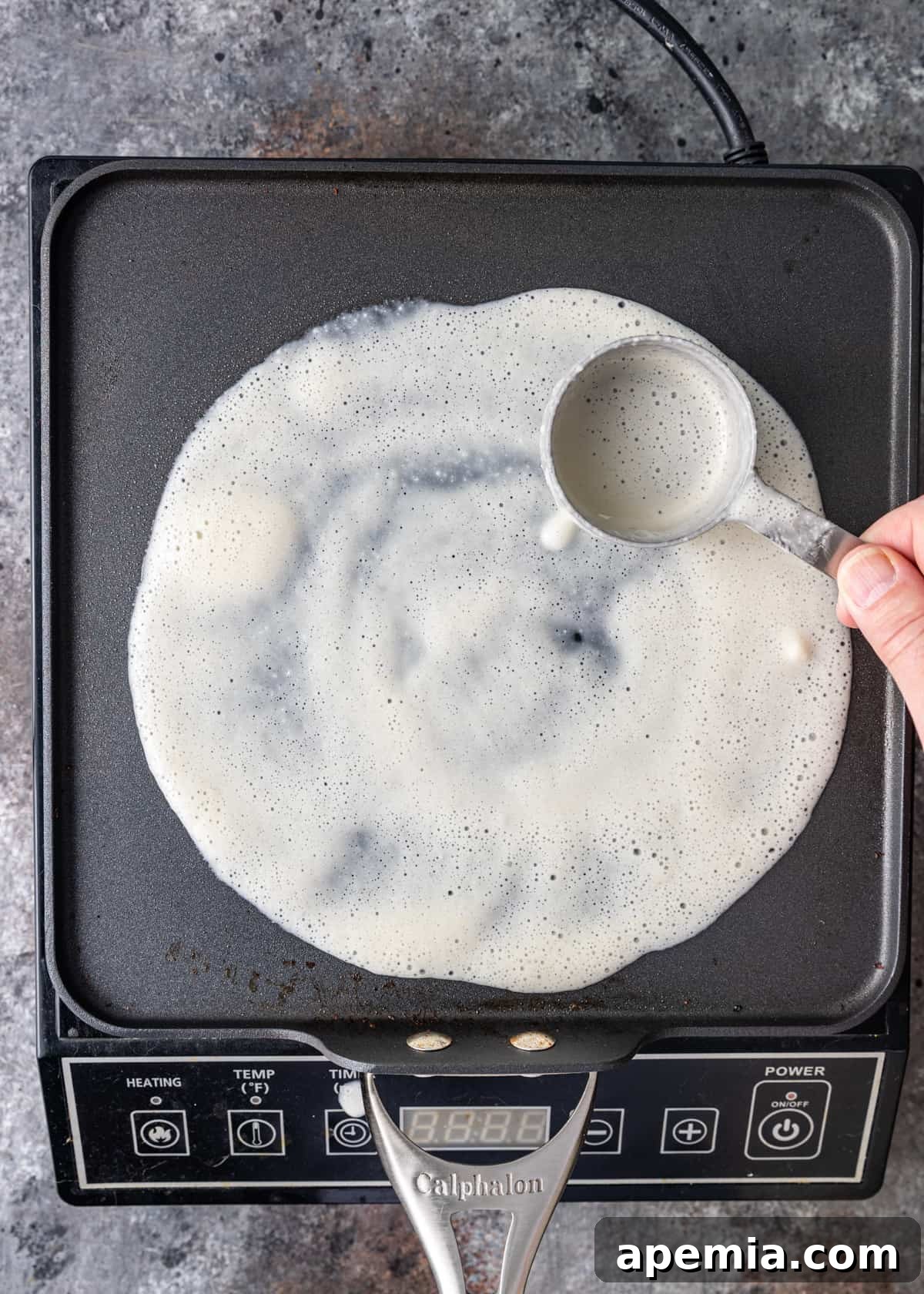 overhead: showing how to make dosa by spooning out batter on griddle