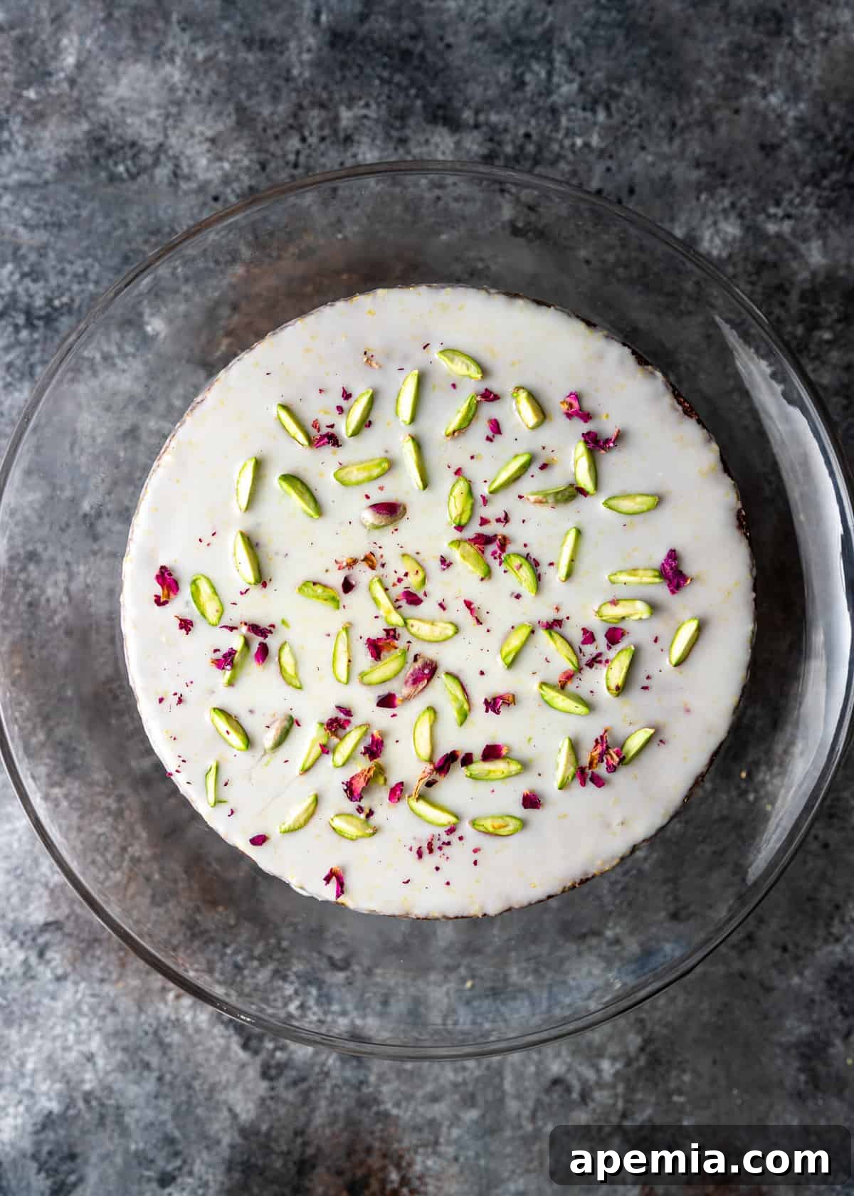 Close-up overhead view of a glazed rose cake on a clear serving plate, showcasing its delicate topping.