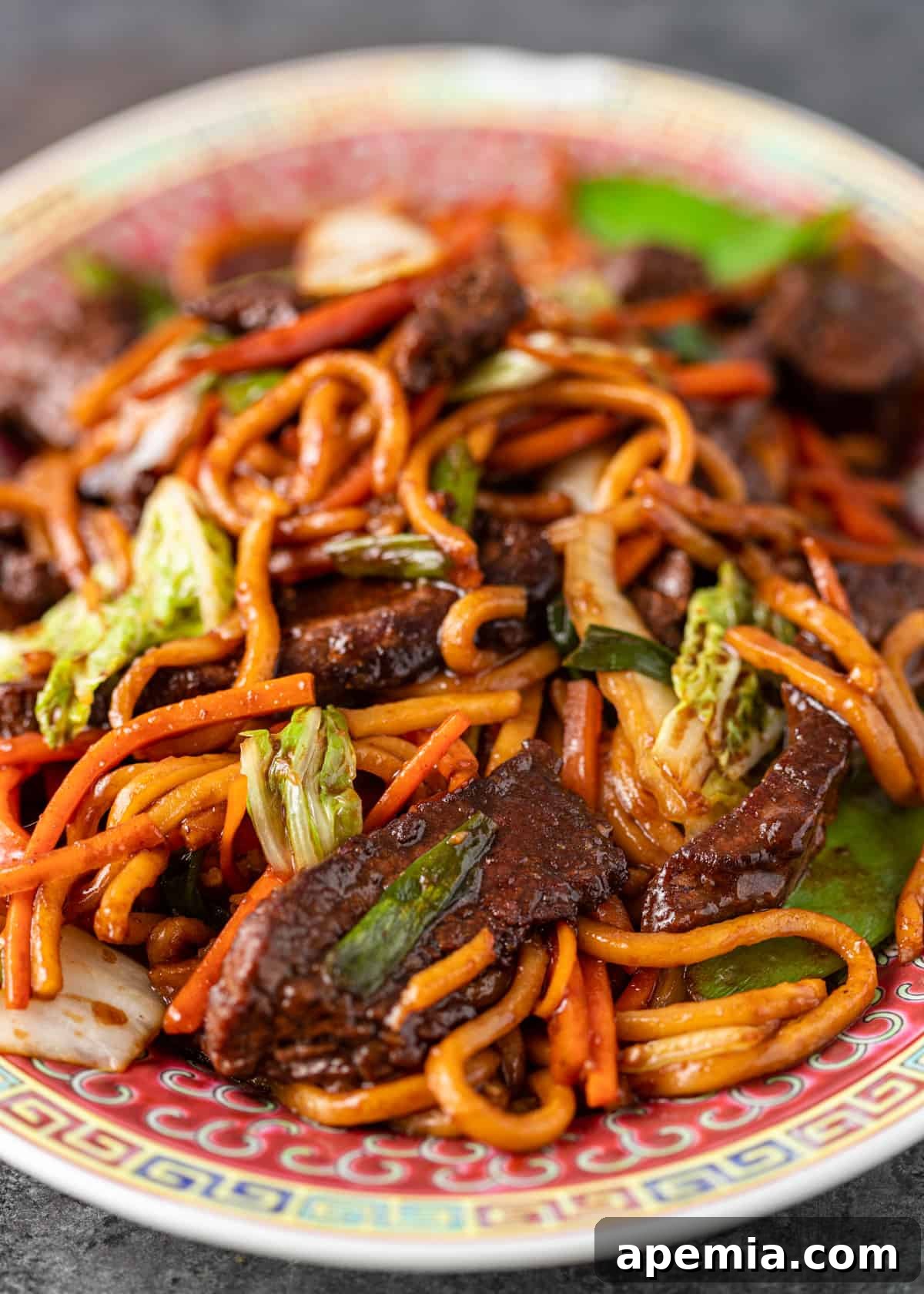 Extreme closeup of Beef Lo Mein, highlighting the rich colors of the noodles, beef, and vegetables, all coated in the flavorful sauce.
