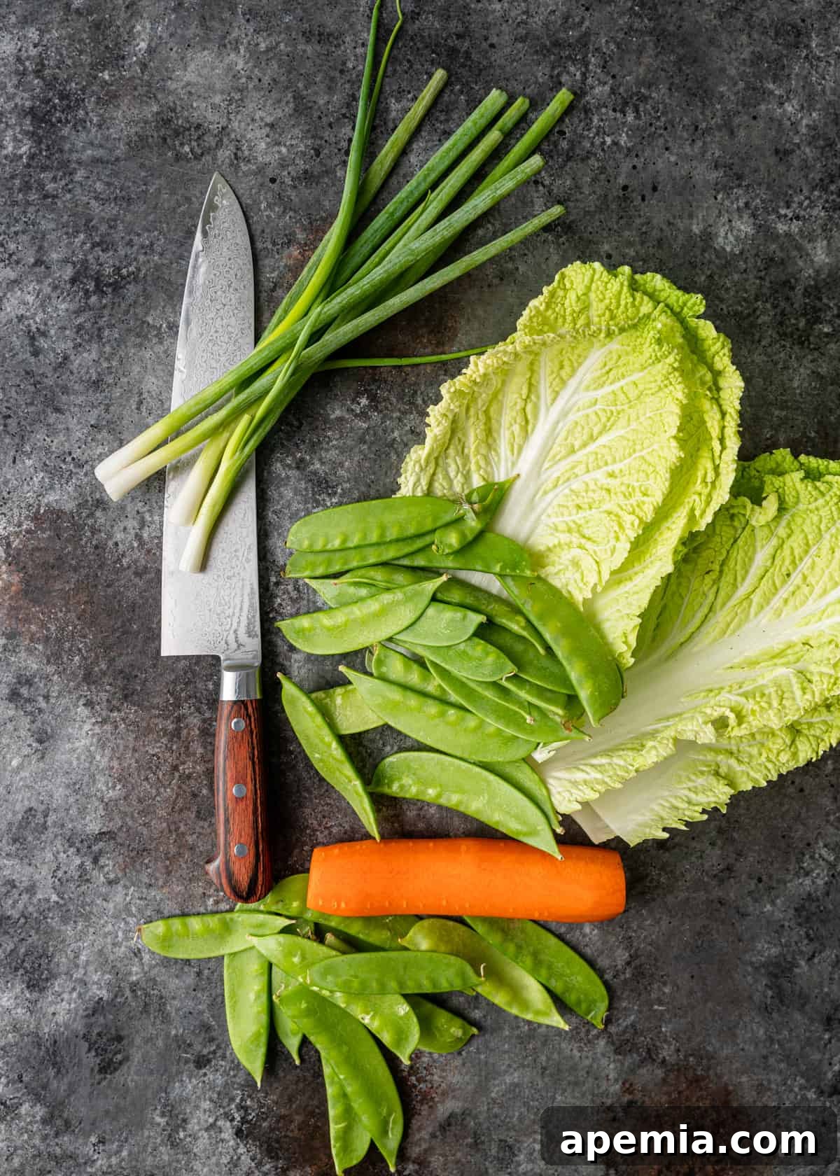 Overhead process shot: Various prepped and chopped vegetables for the Beef Lo Mein recipe, including cabbage, carrots, green onions, and snow peas.