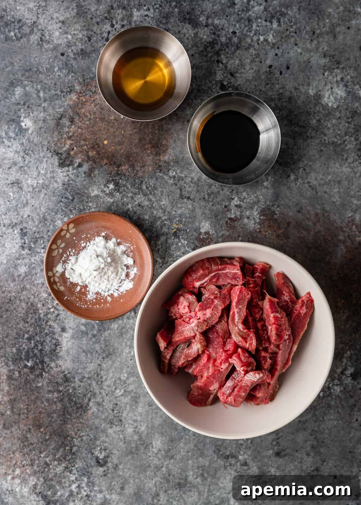 Overhead process shot: Sliced beef marinating in a bowl with sauces and cornstarch, ensuring tenderness and flavor for the lo mein.