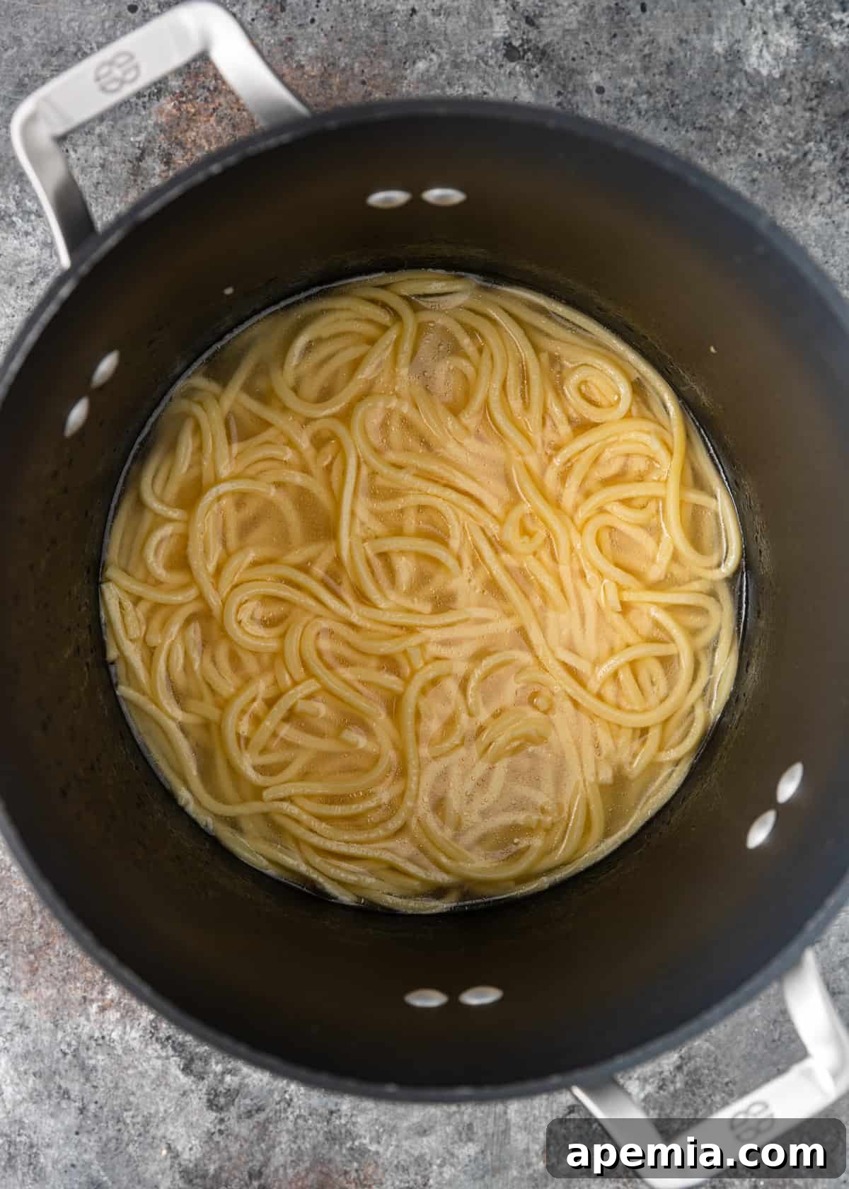 Overhead process shot: Fresh lo mein noodles cooking in a pot of boiling water, preparing them for the stir-fry.