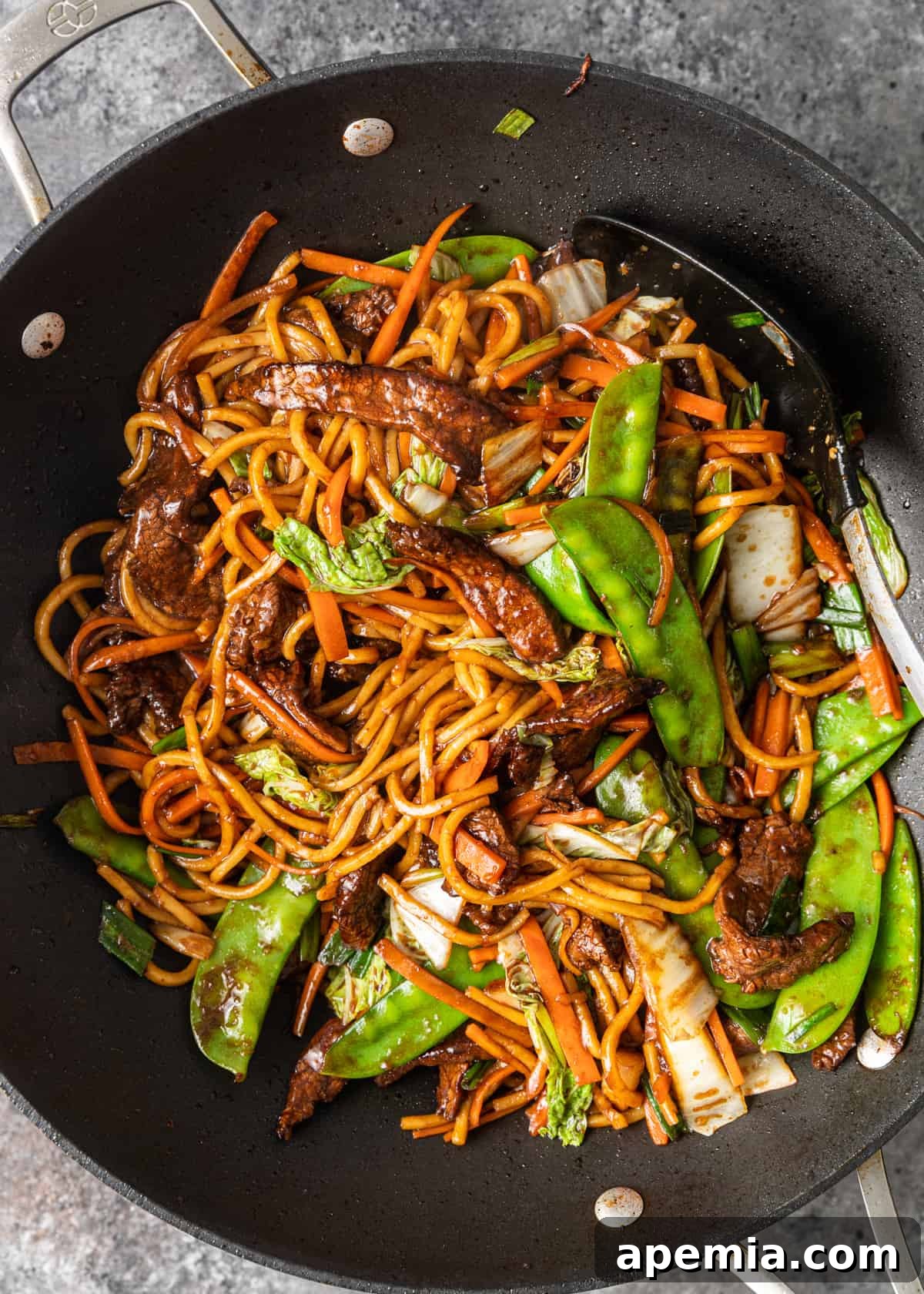 Overhead shot of our Beef Lo Mein recipe sizzling and being tossed in a traditional wok, showing the combination of ingredients.