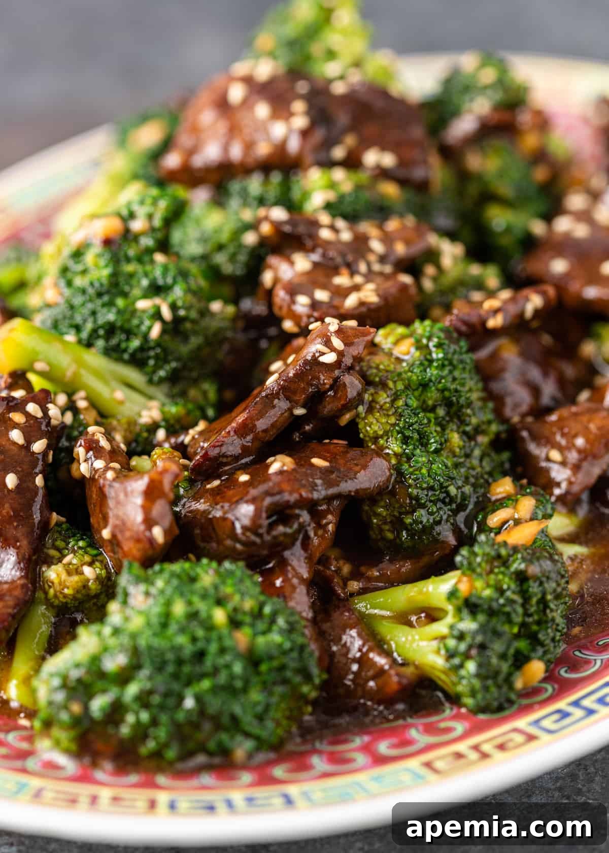 closeup shot of tender broccoli beef served on a white plate with steamed rice